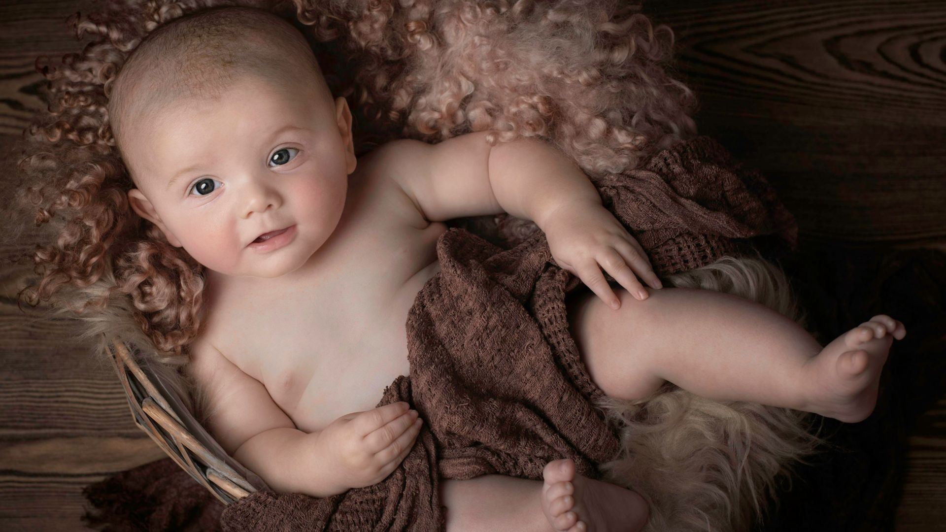 baby lying on brown textile