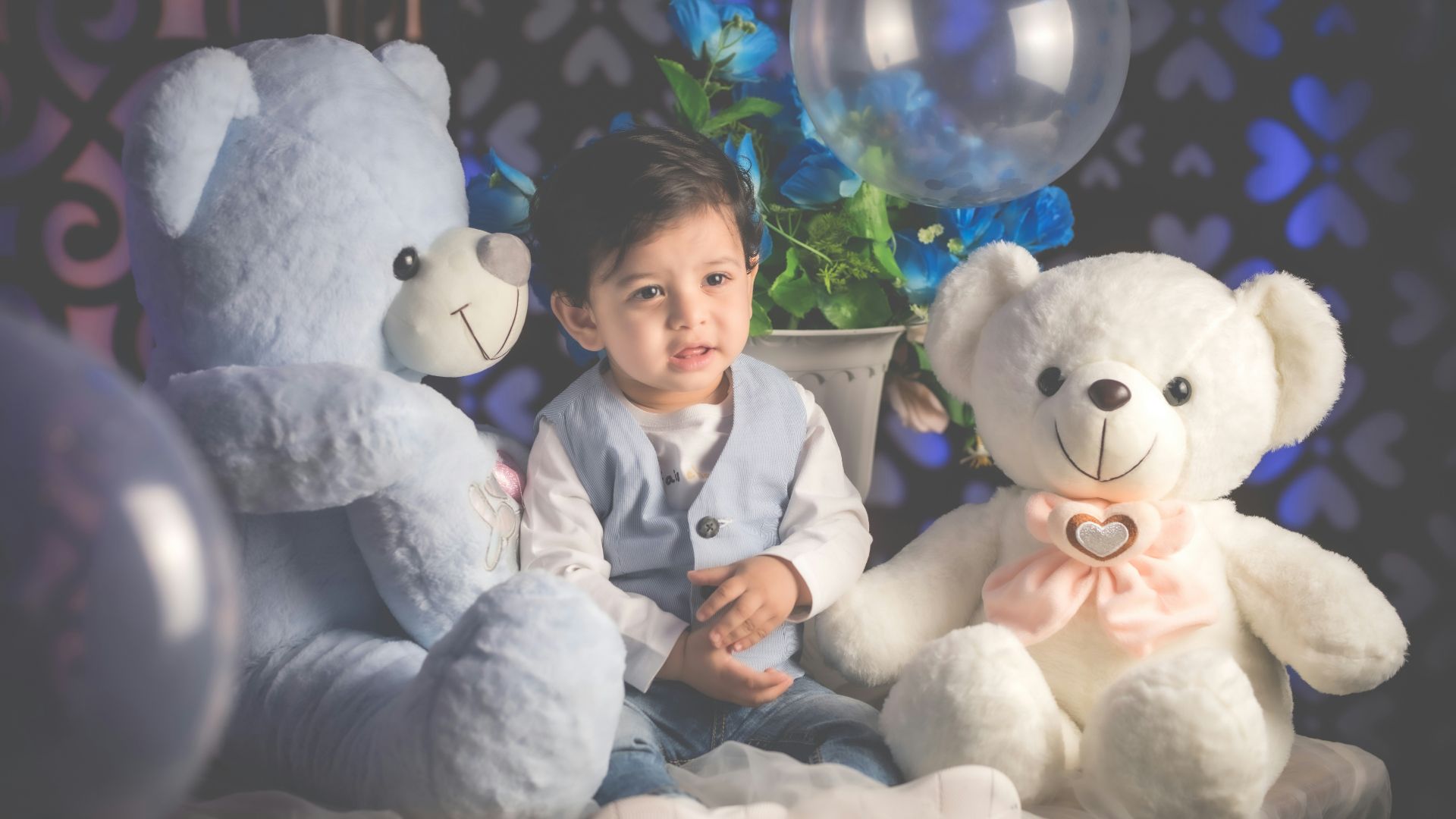 boy in blue dress shirt sitting beside white bear plush toy