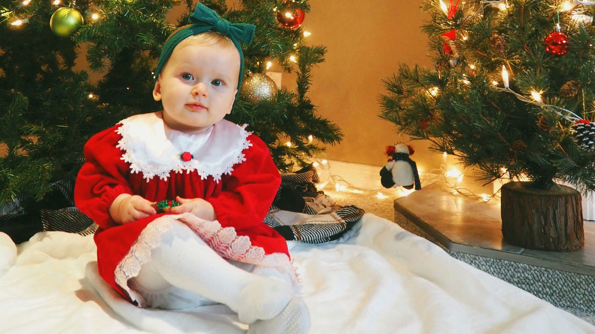 girl in red and white santa costume standing beside green christmas tree