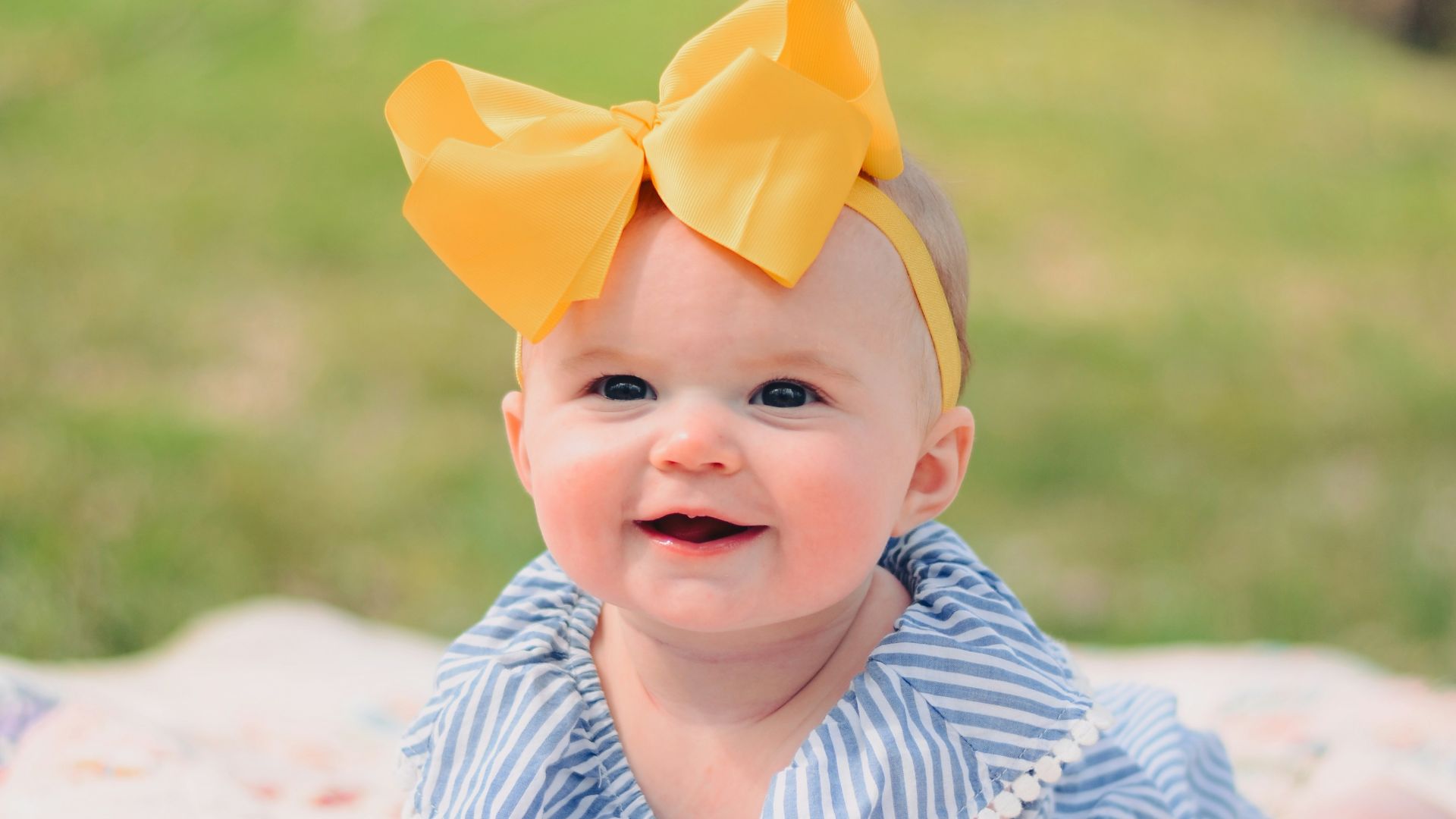 smiling baby lying forward on pink textile