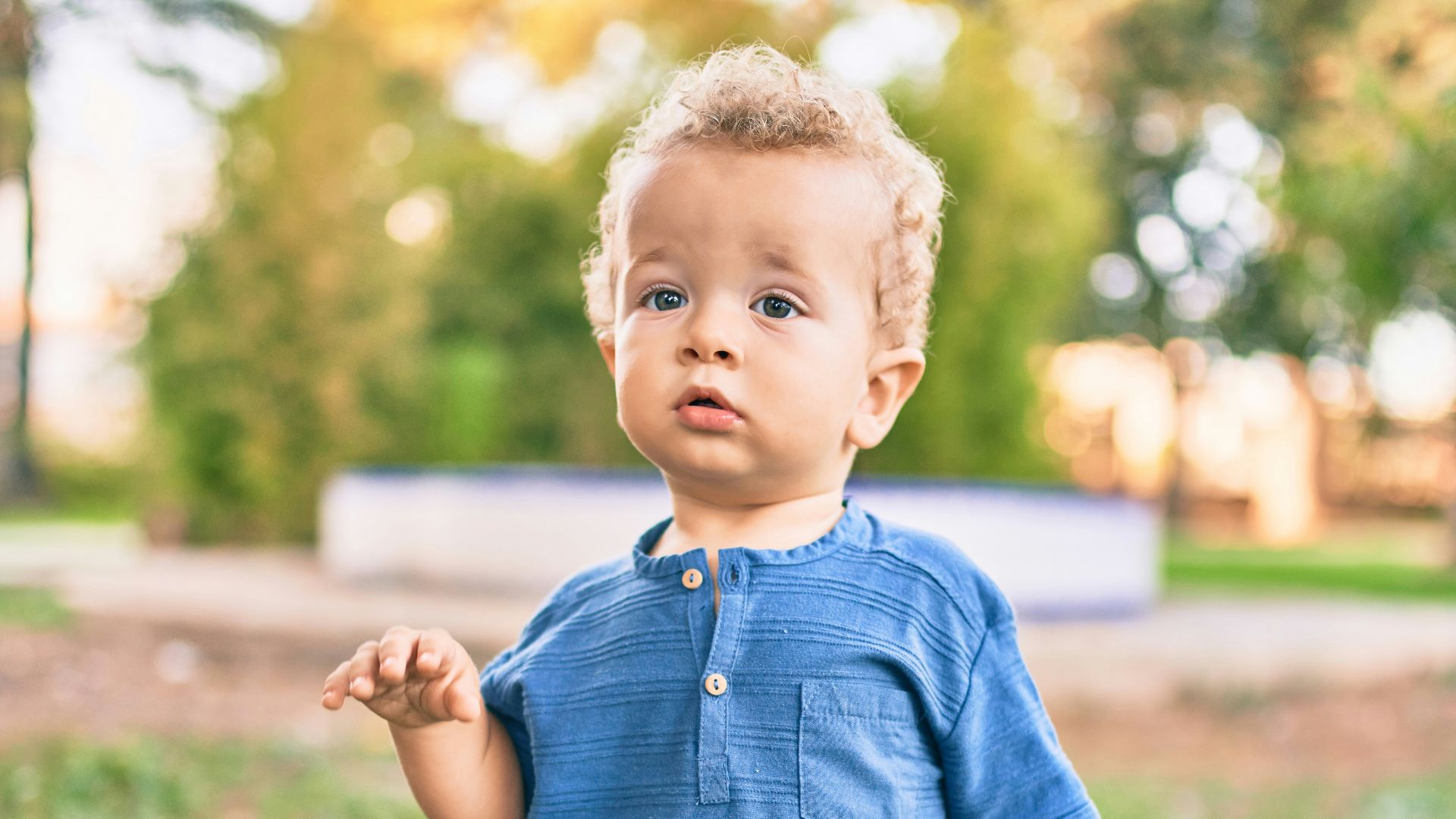 boy in blue polo shirt and blue denim shorts standing on green grass field during daytime