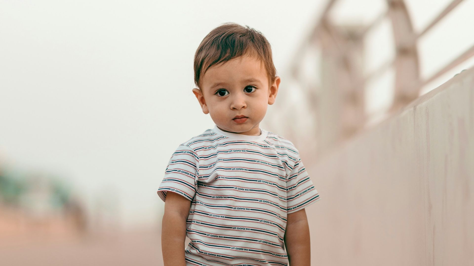 boy in white and gray striped t-shirt and blue denim shorts standing on brown wooden