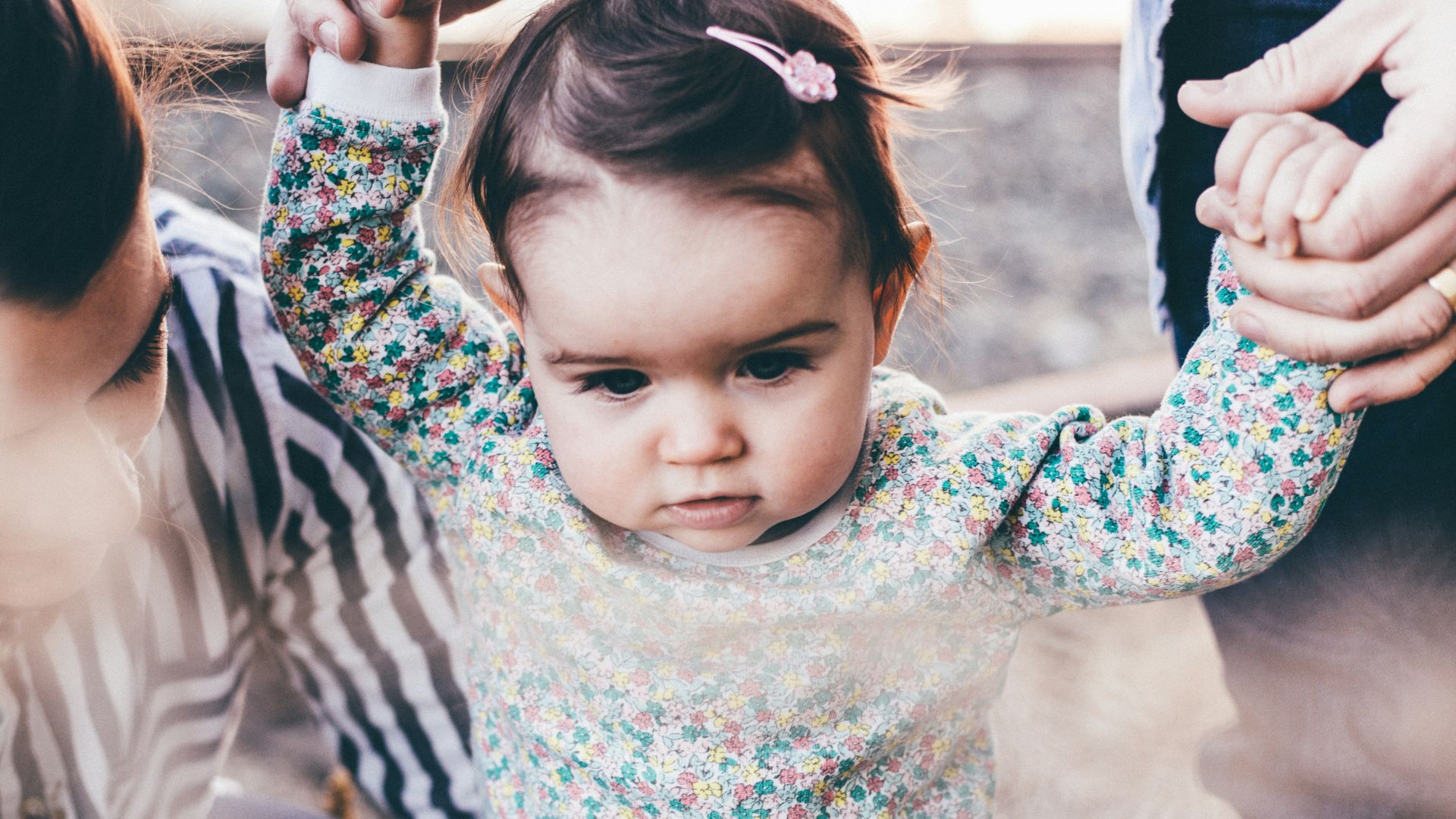 woman holding girl while learning to walk taken at daytime