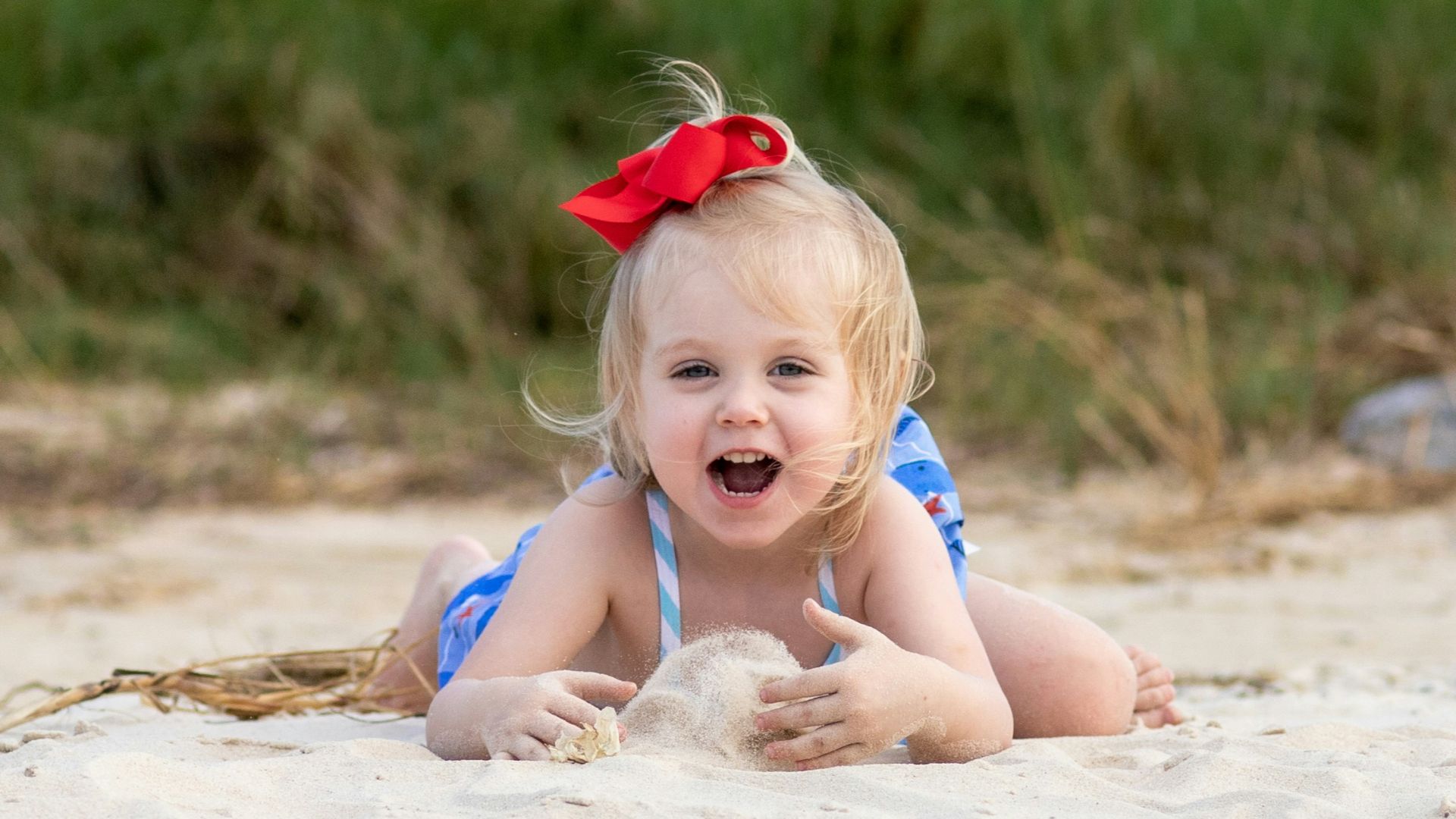 girl in red headband sitting on sand during daytime