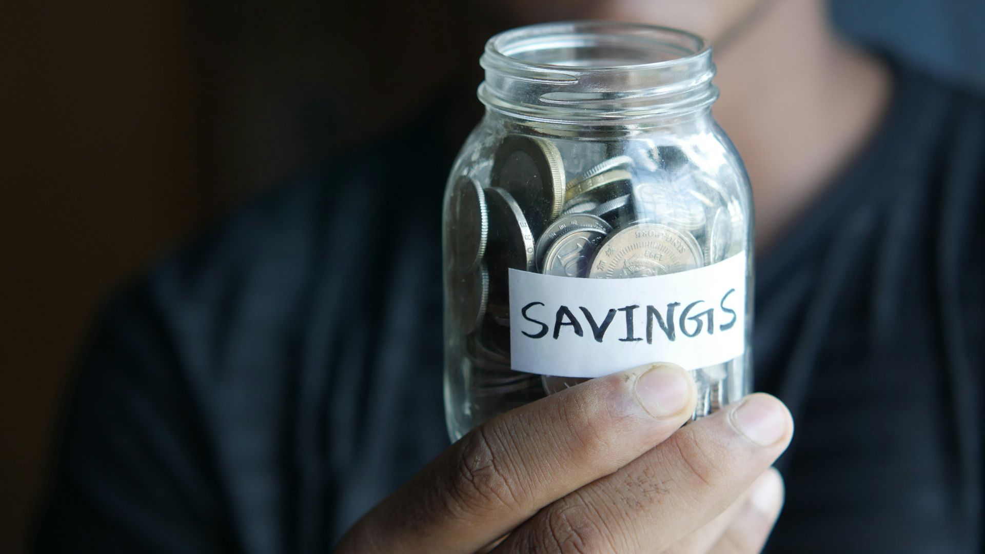 a man holding a jar with a savings label on it