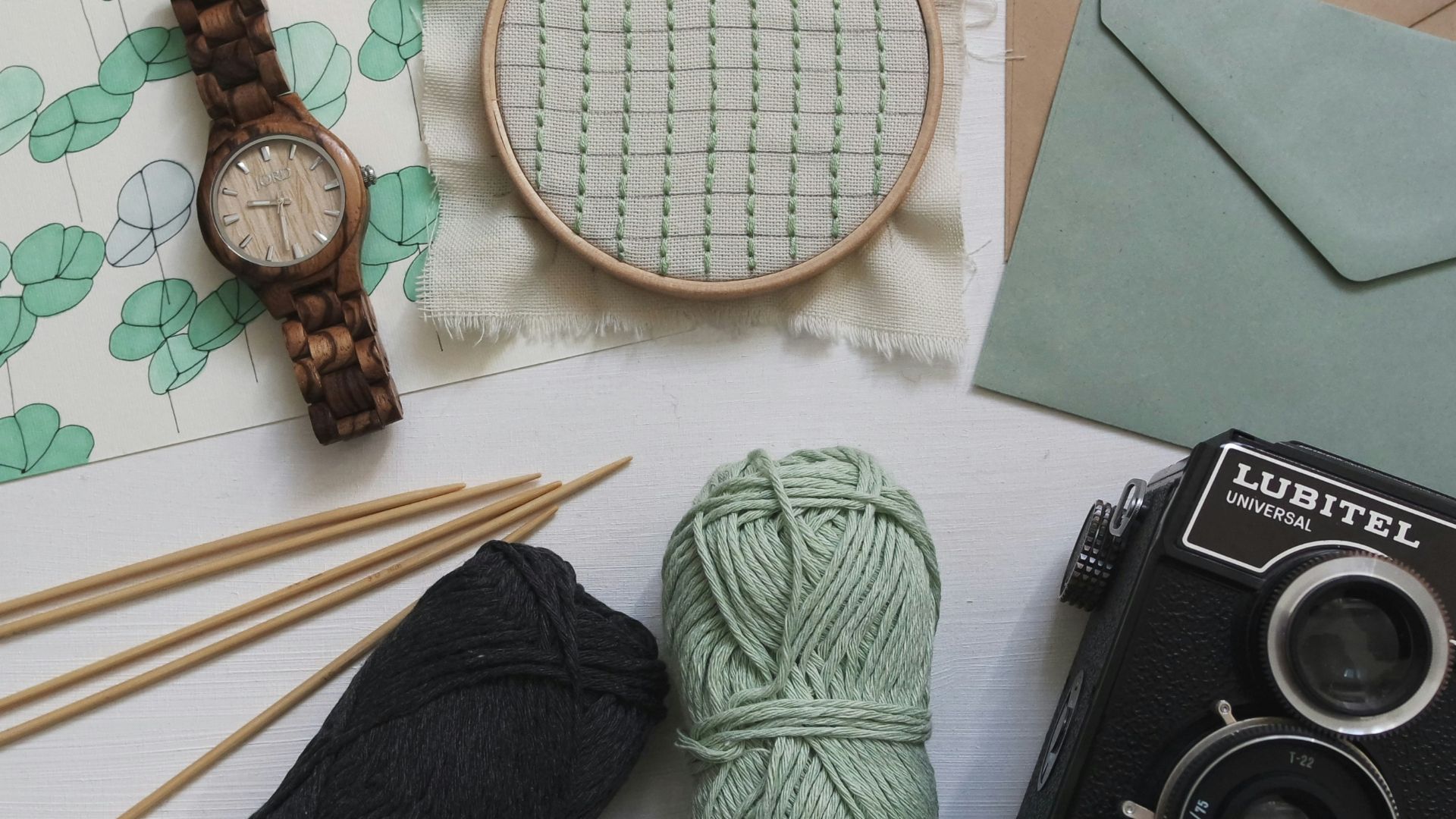 green and black yarns with round brown watch and black Lubitel camera