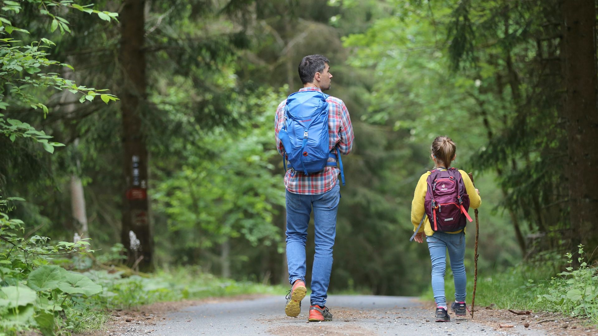 man in blue jacket and blue denim jeans walking on dirt road during daytime