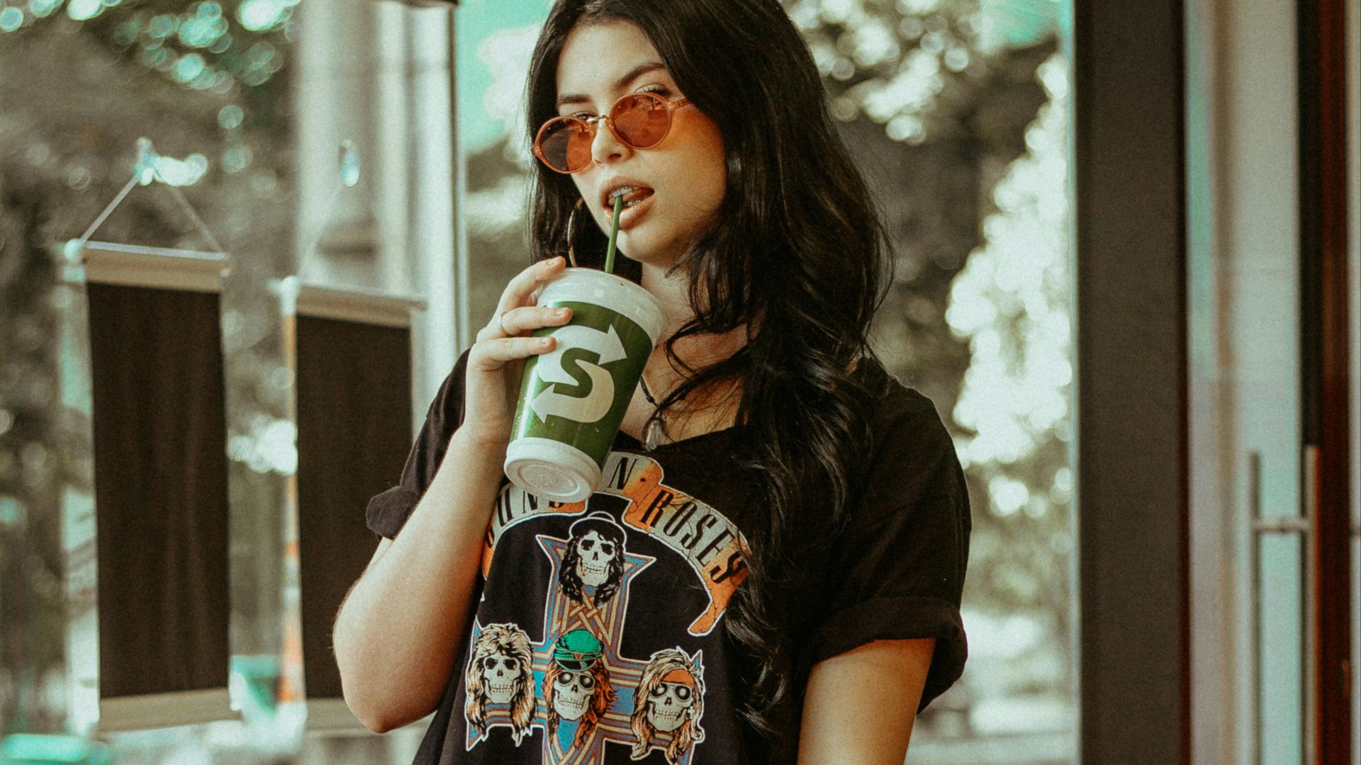woman licking green straw from tumbler