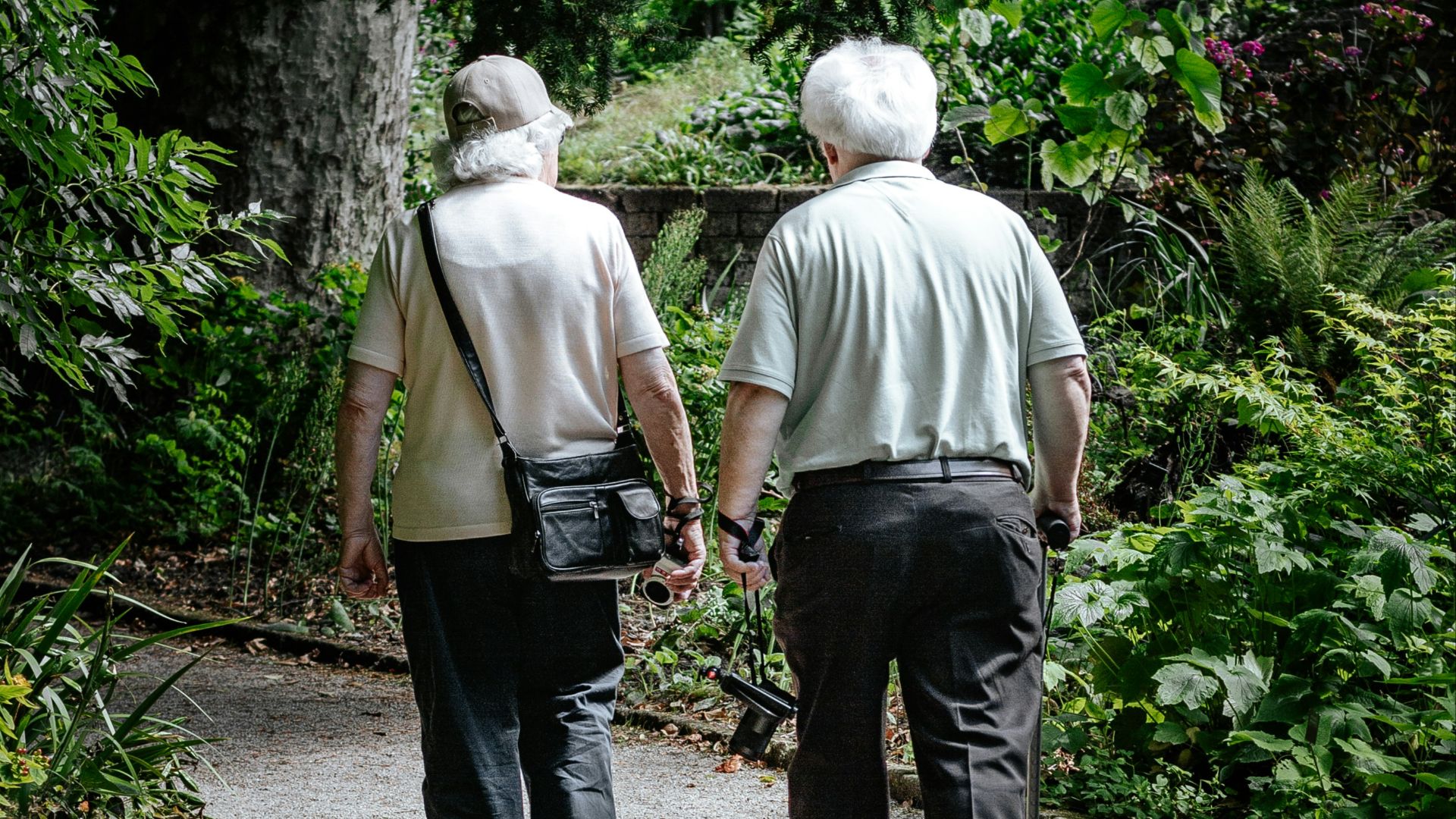 man in white shirt and blue denim jeans walking on pathway