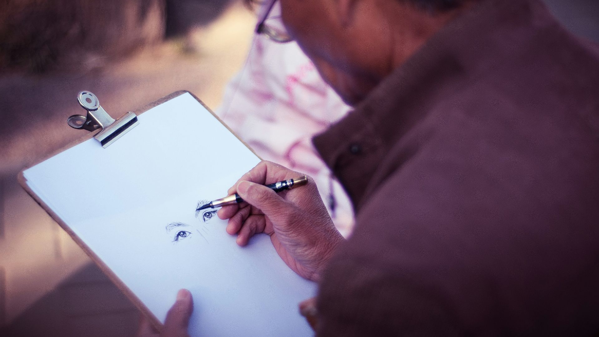 man sketching face on white printer paper