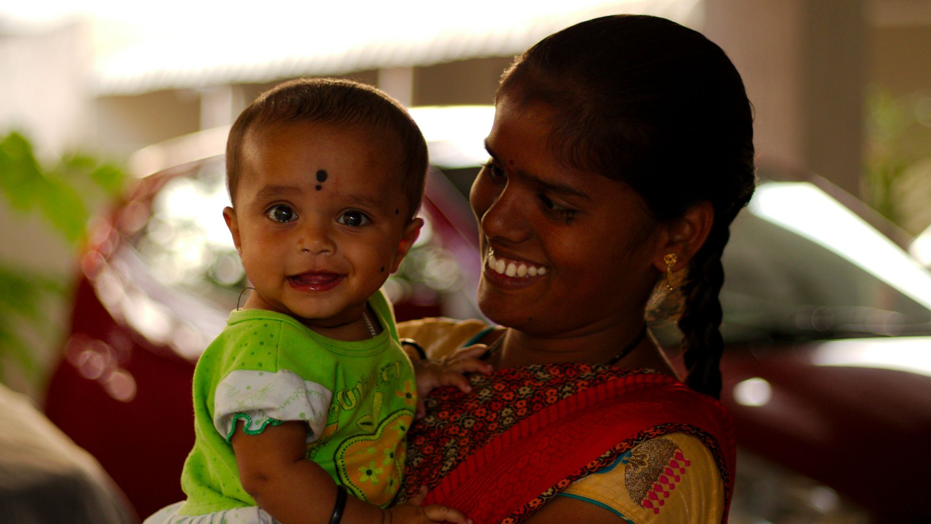 man in white shirt carrying baby in green and white shirt
