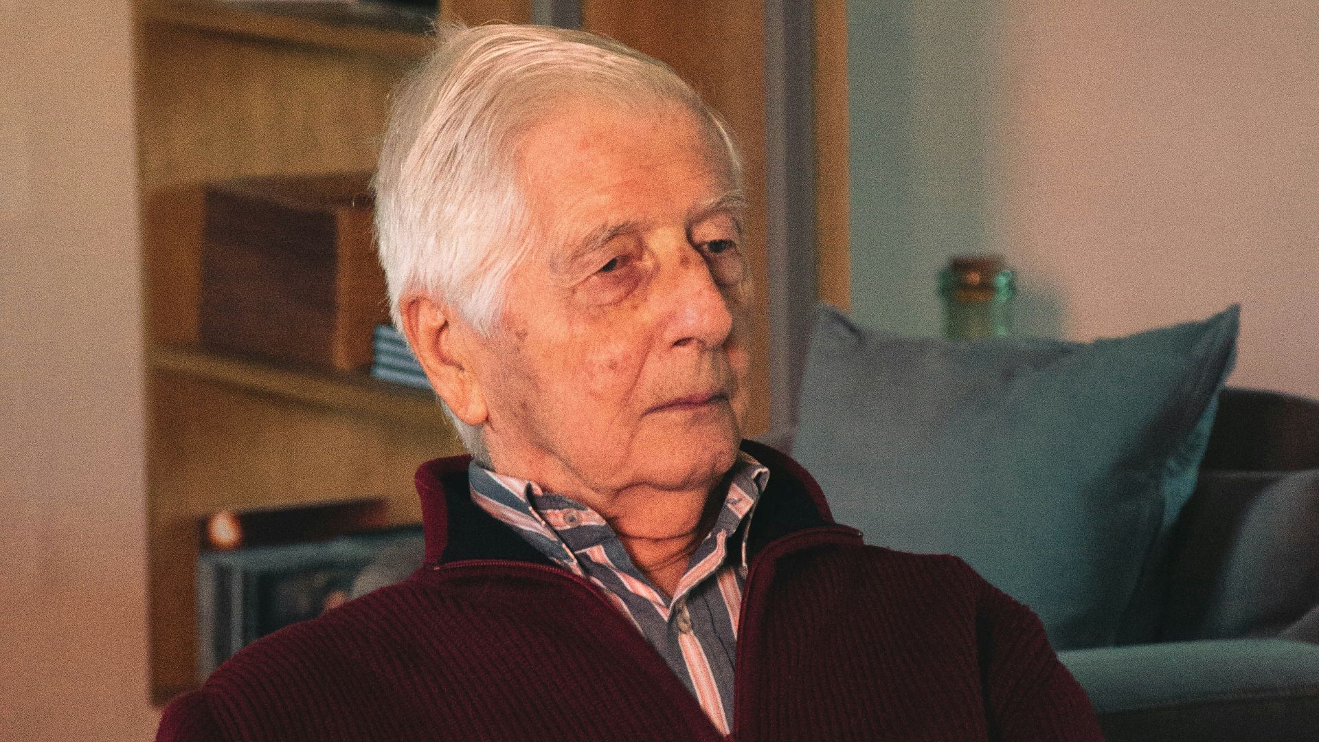 man in red and black jacket sitting on black couch