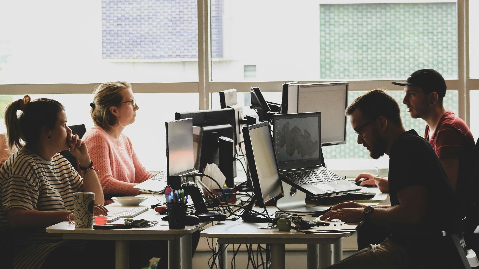 woman in pink shirt sitting in front of black laptop computer