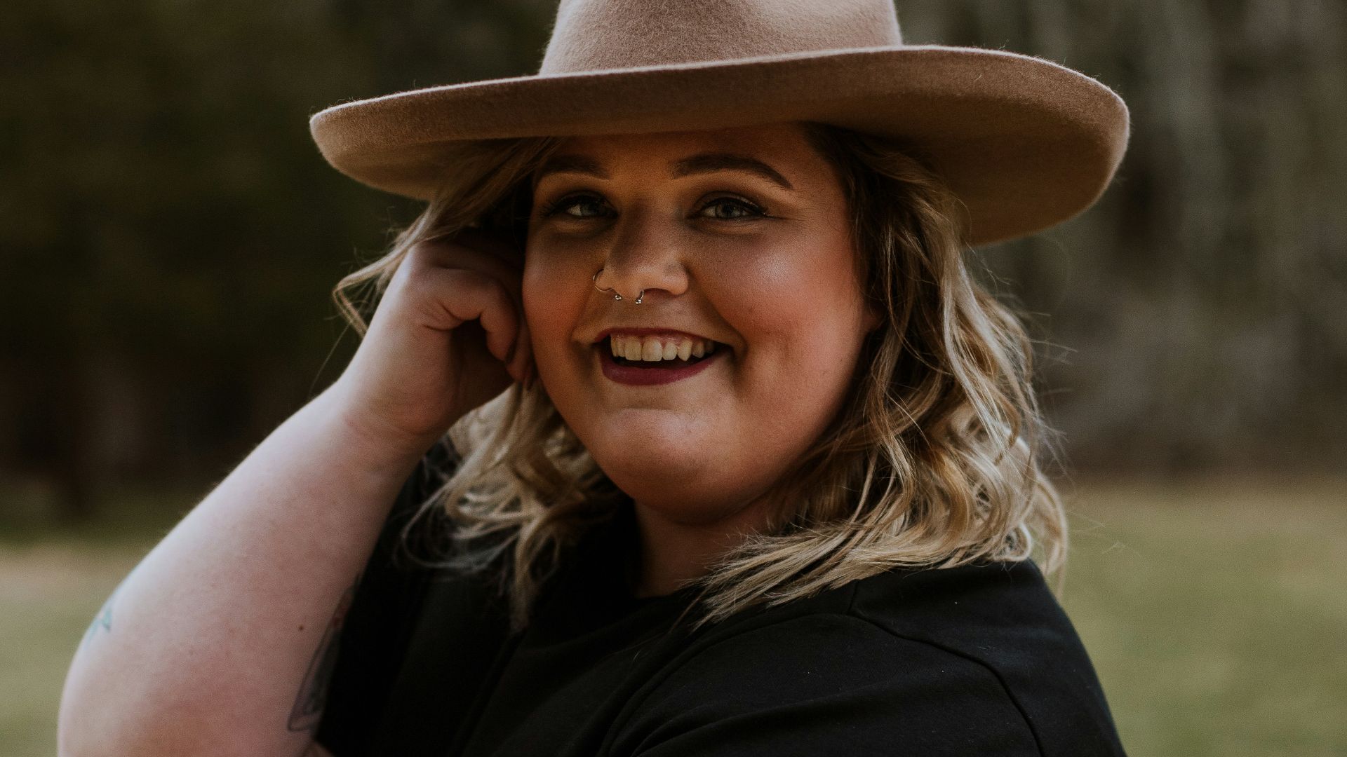 woman in black sleeveless dress wearing brown fedora hat