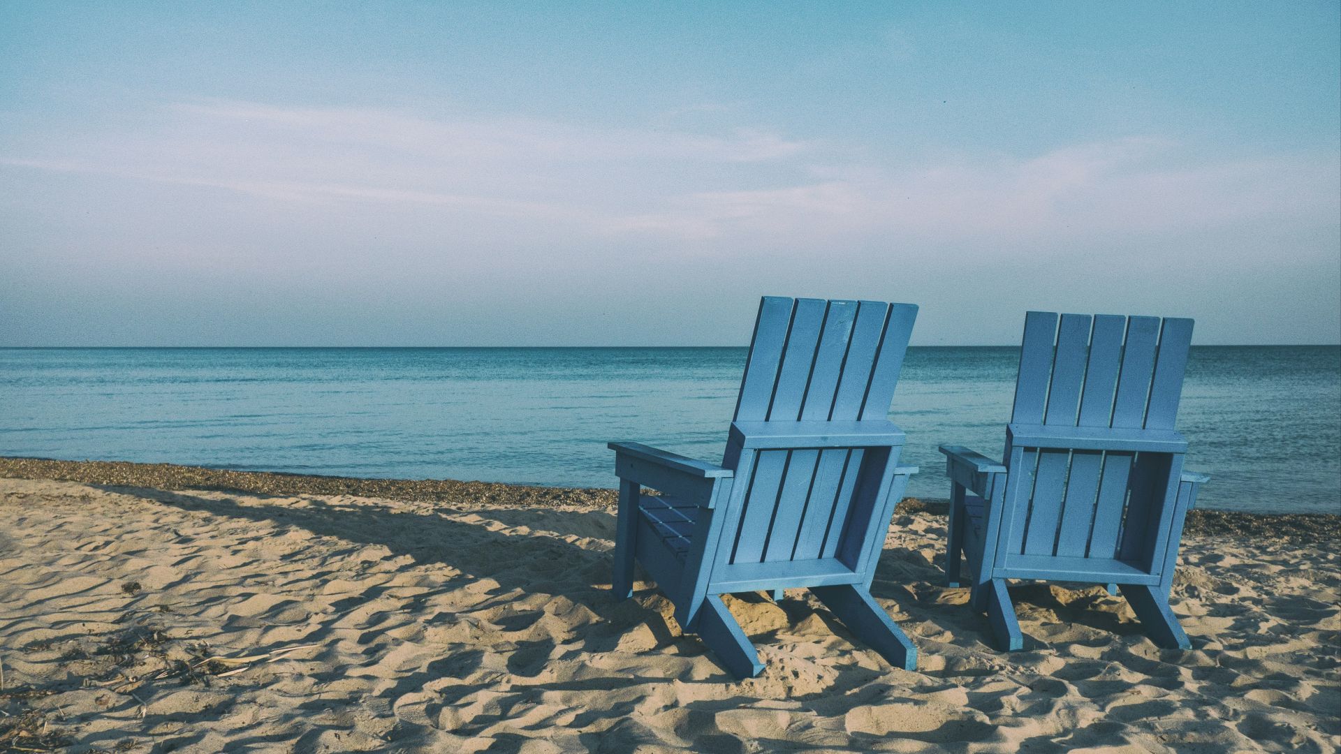 two blue beach chairs near body of water