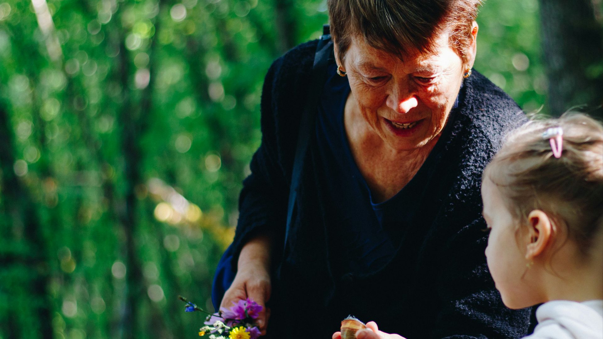woman in black long sleeve shirt holding purple flower