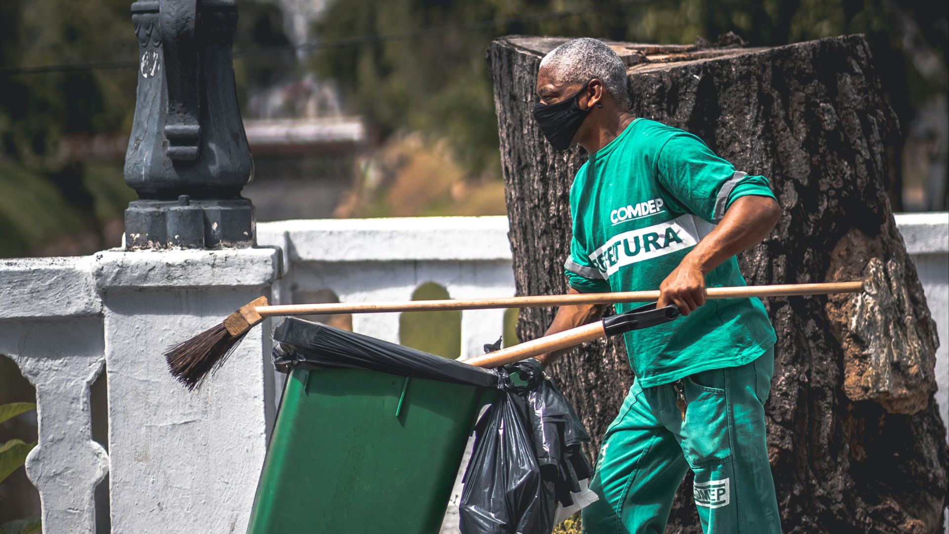 man in blue and white plaid shirt and red pants holding green plastic container