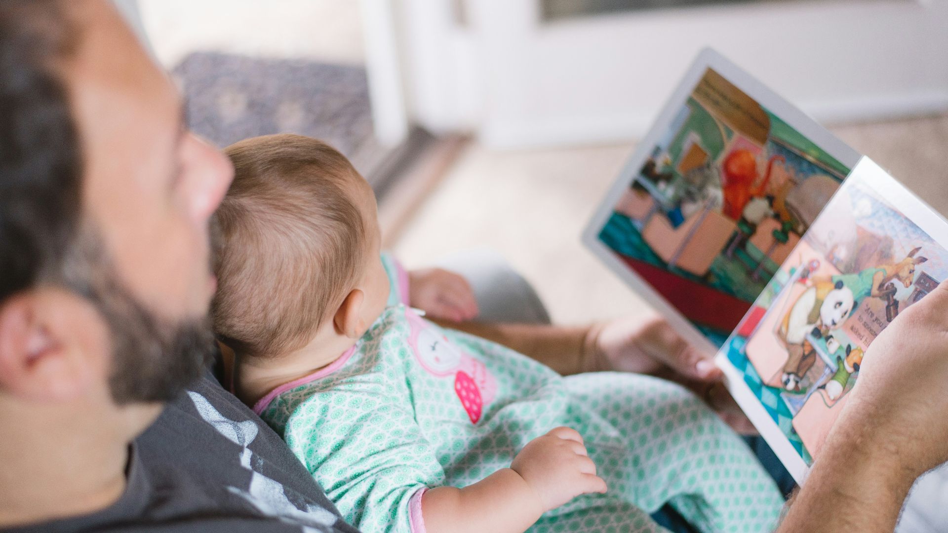 person carrying baby while reading book