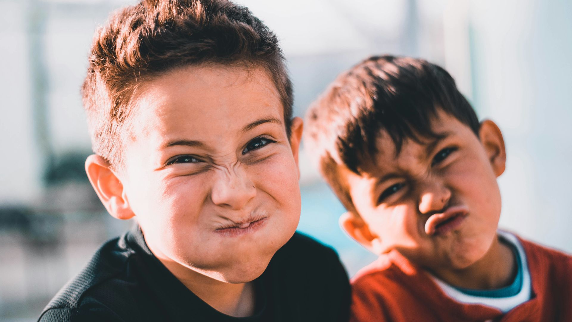shallow focus photography of two boys doing wacky faces