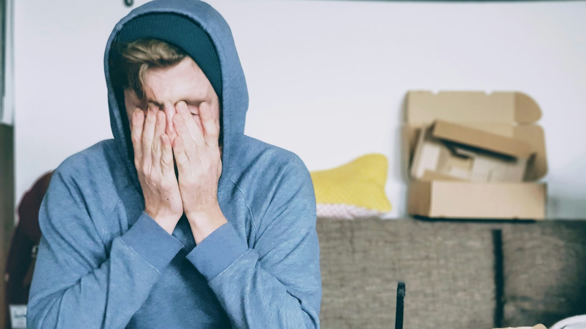 man covering face with both hands while sitting on bench