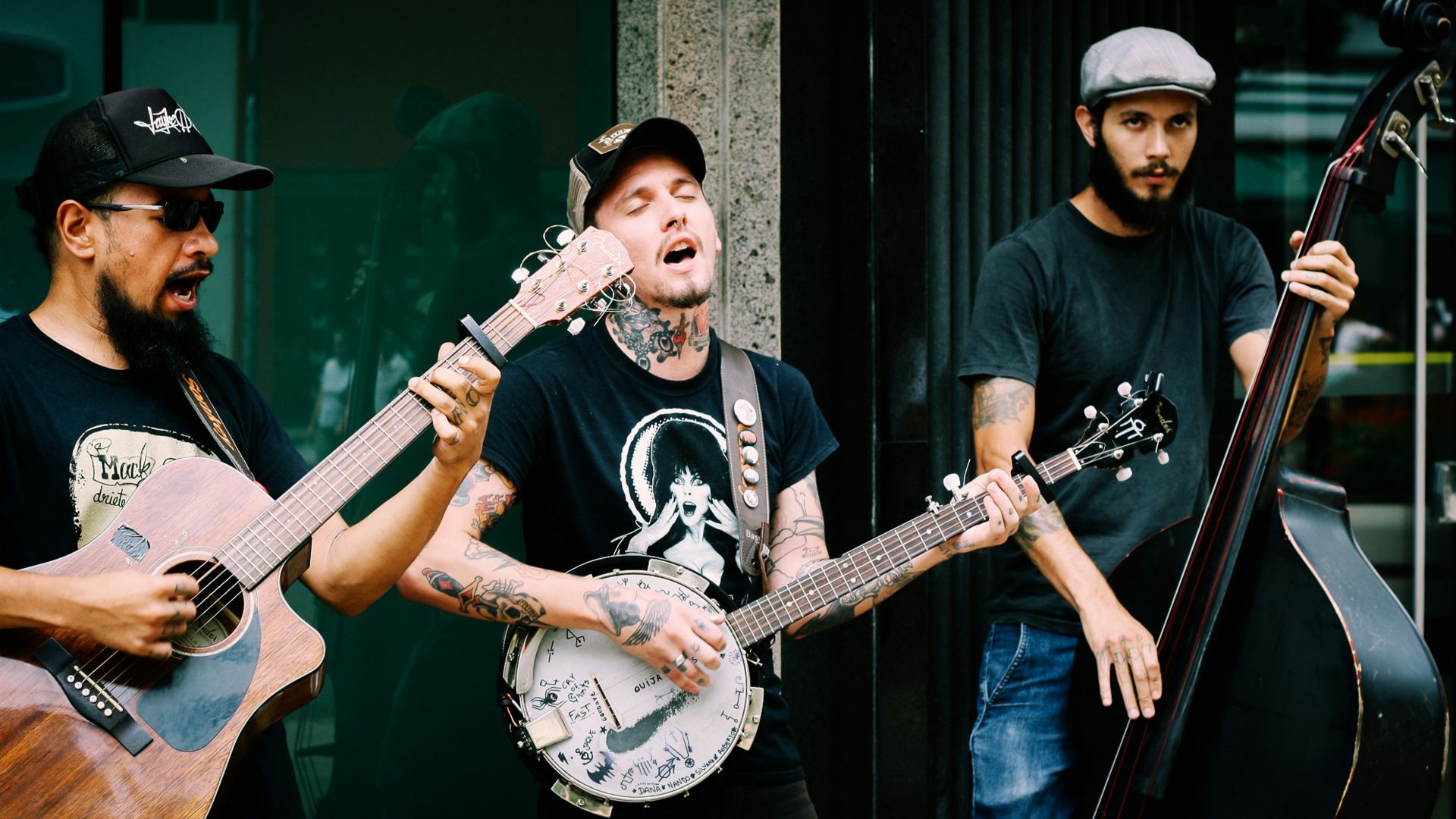 three men playing stringed instruments during daytime