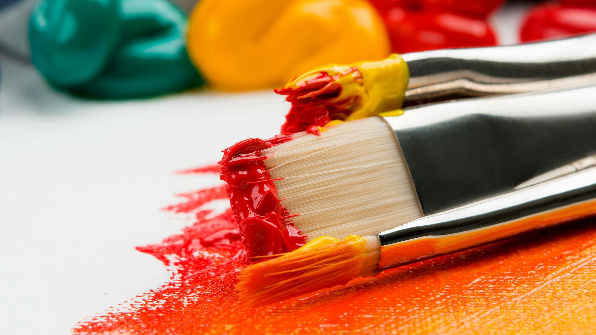 three silver paint brushes on white textile