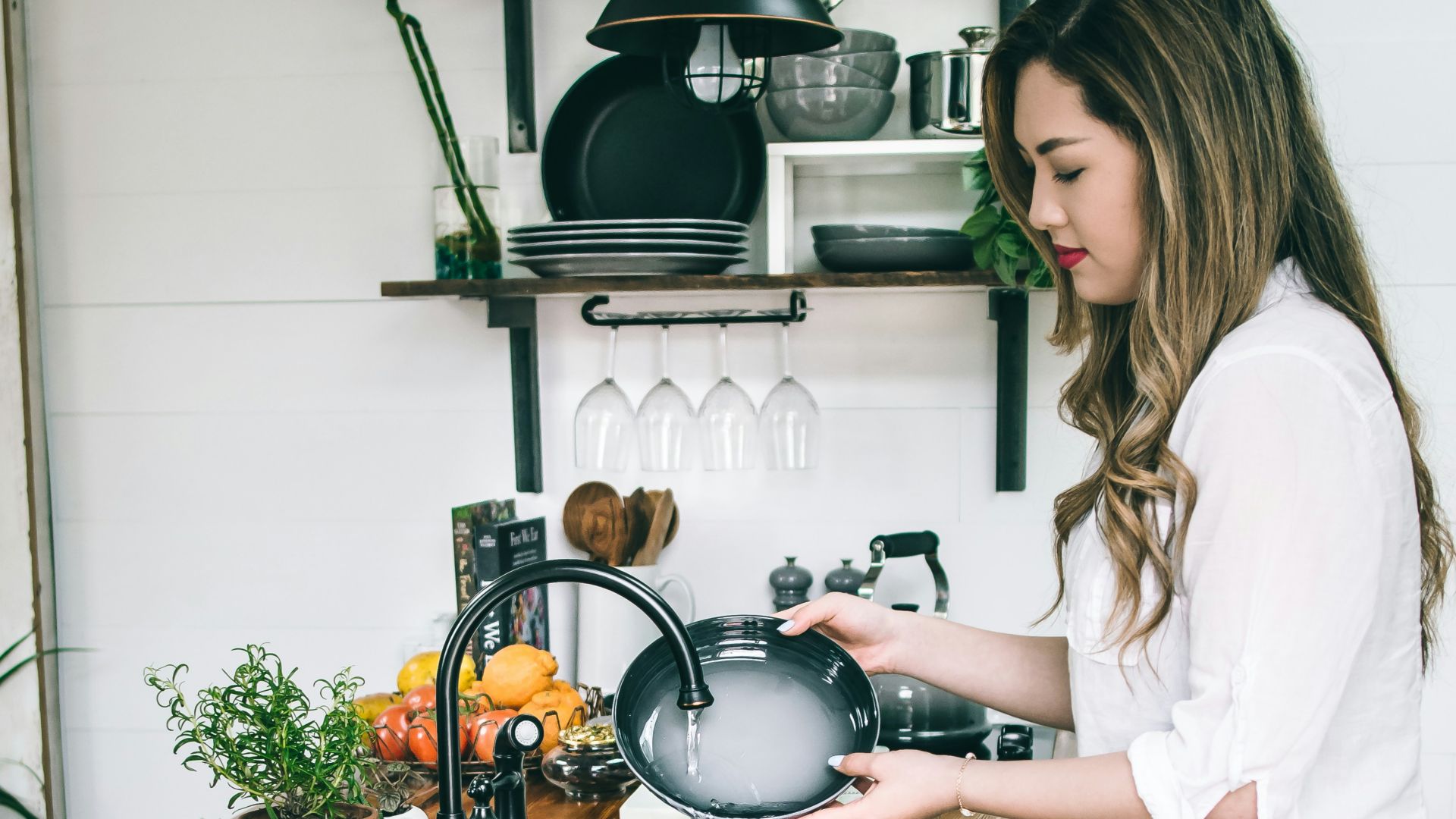 woman wearing white blouse washing dish on the faucet