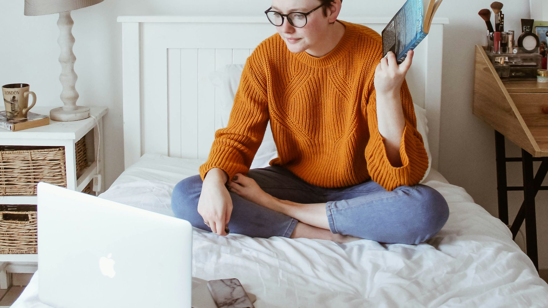 woman sitting on bed facing laptop