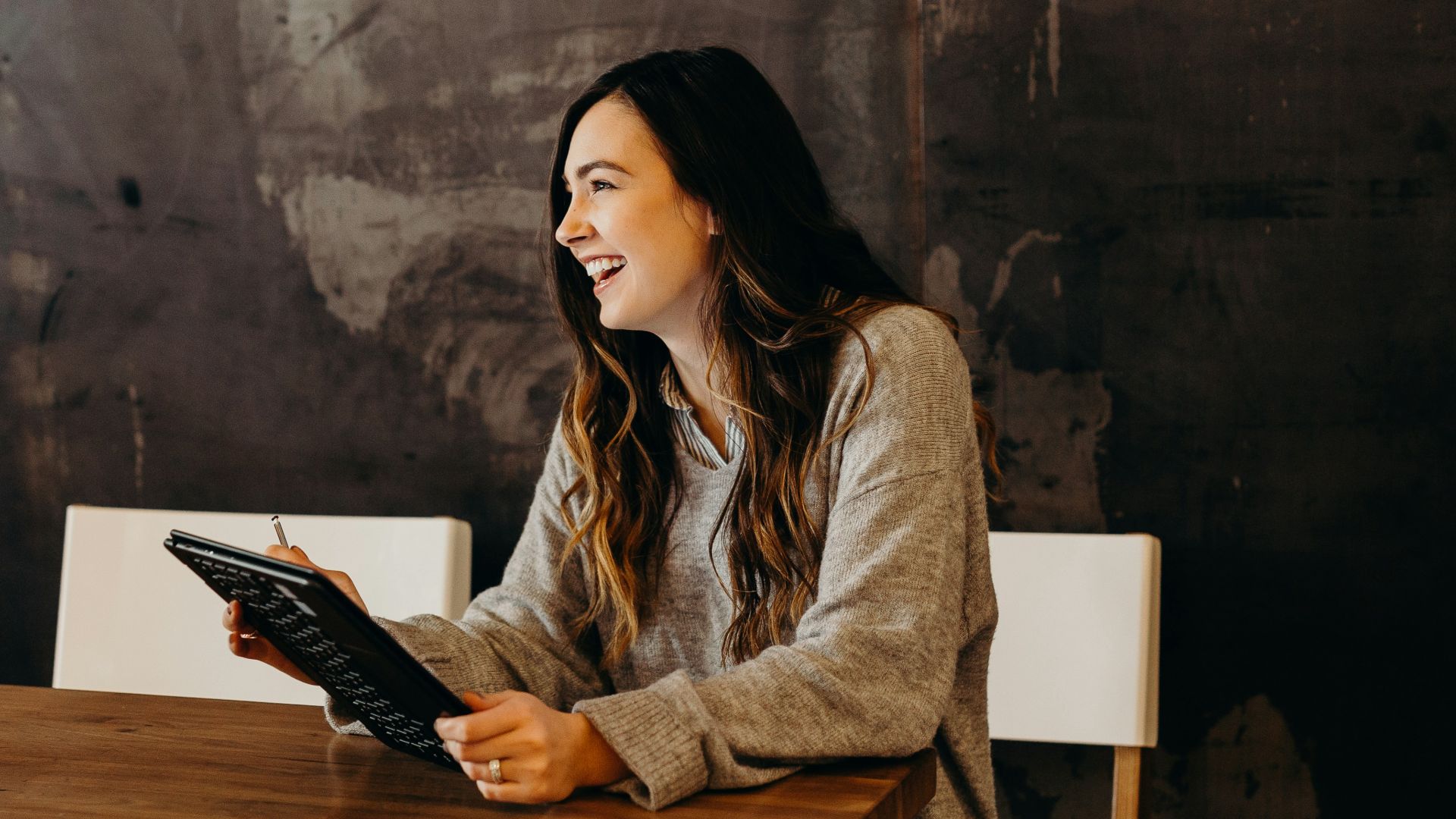 woman sitting around table holding tablet