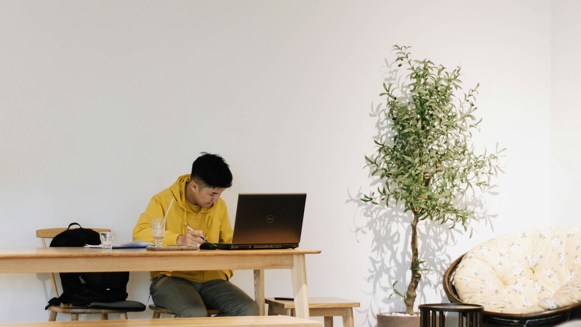 man in yellow dress shirt sitting on chair in front of laptop computer