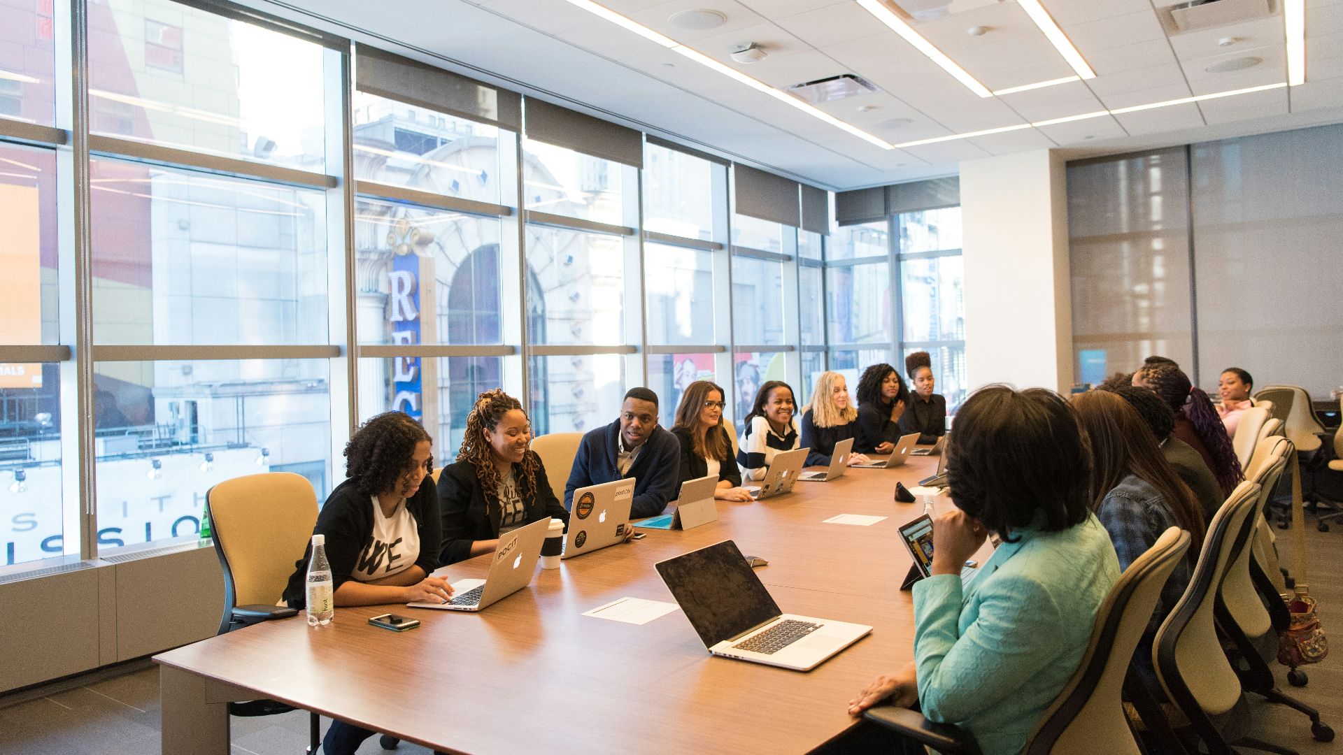 group of people sitting beside rectangular wooden table with laptops
