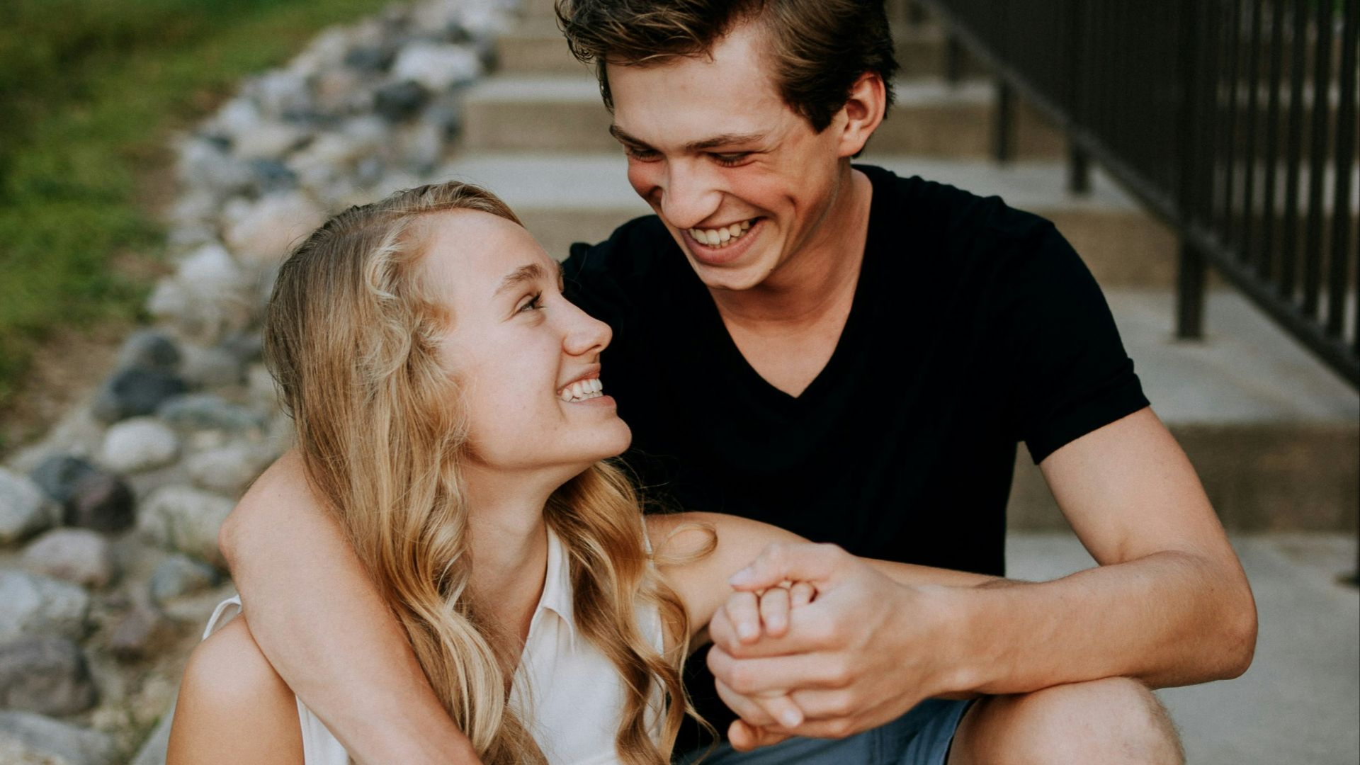 man holding the hand of a woman while siting on concrete staircase