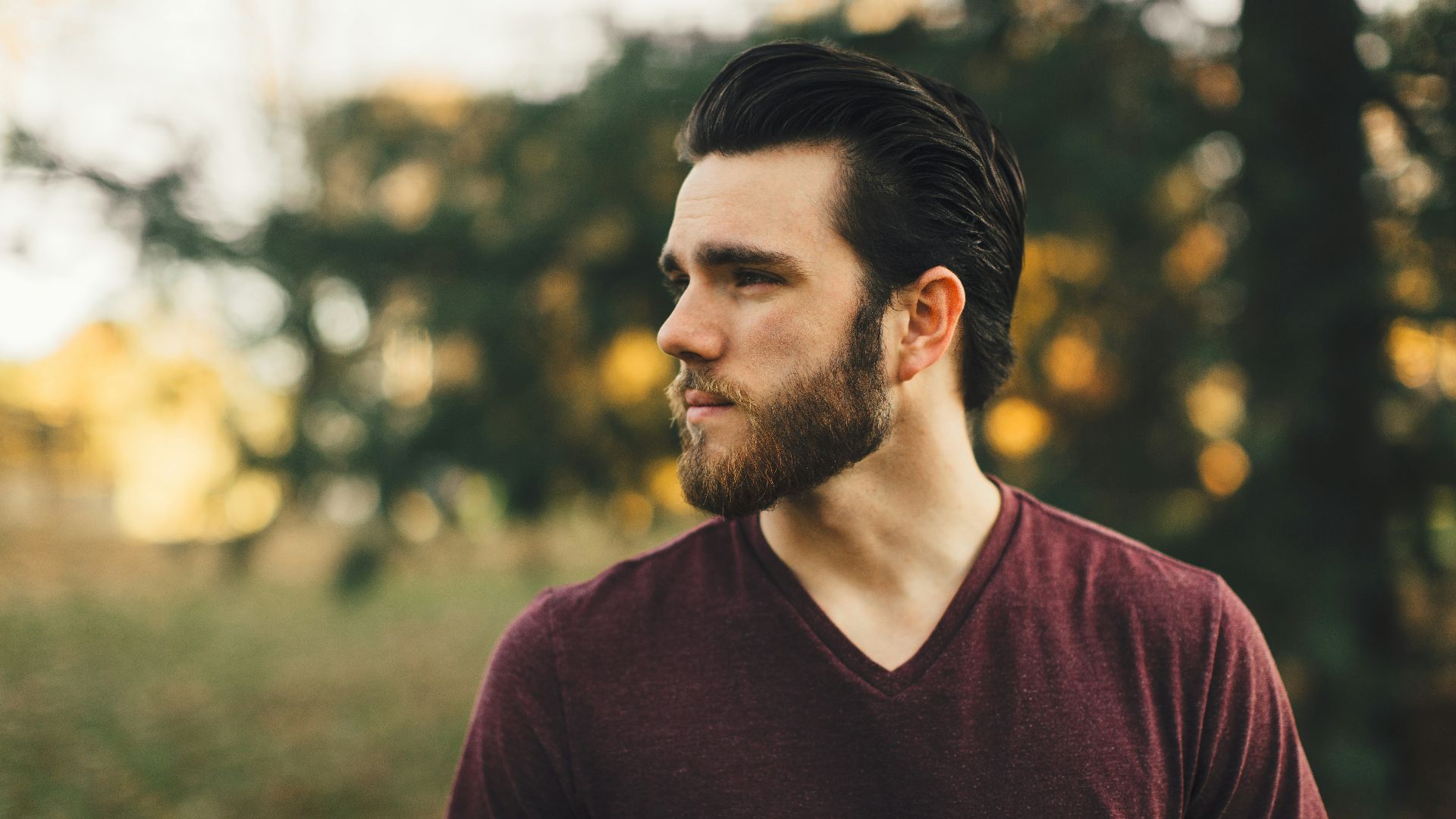 man wearing maroon V-neck t-shirt in forest