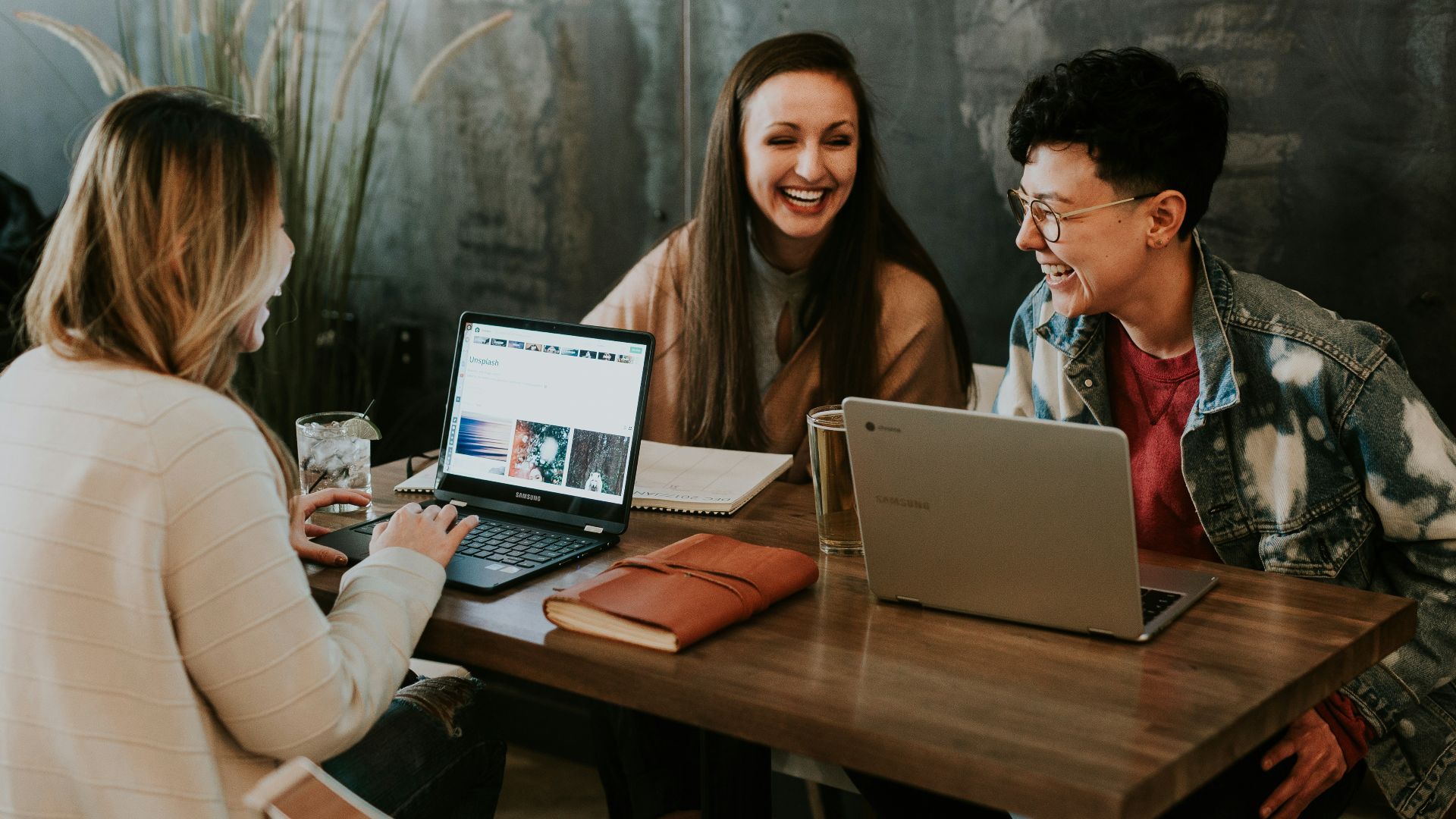 three people sitting in front of table laughing together