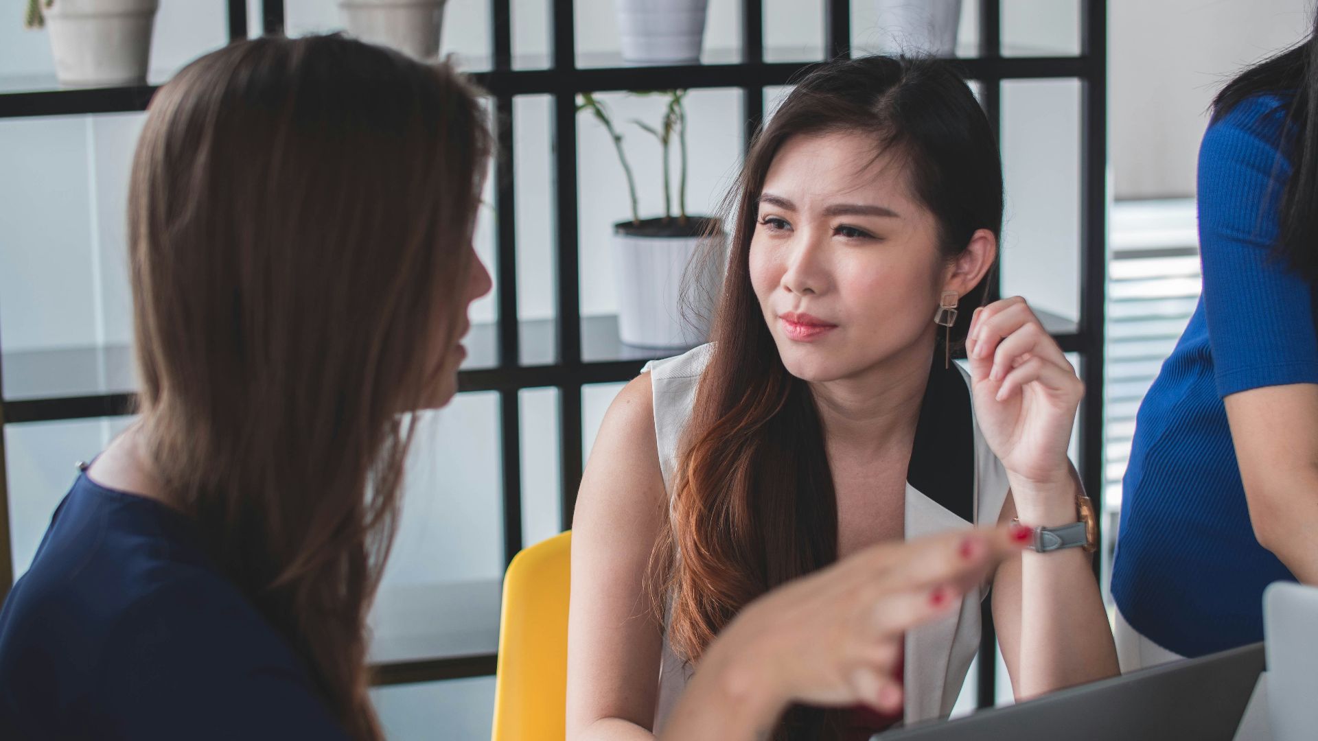 woman sitting on yellow armless chair near gray laptop computer