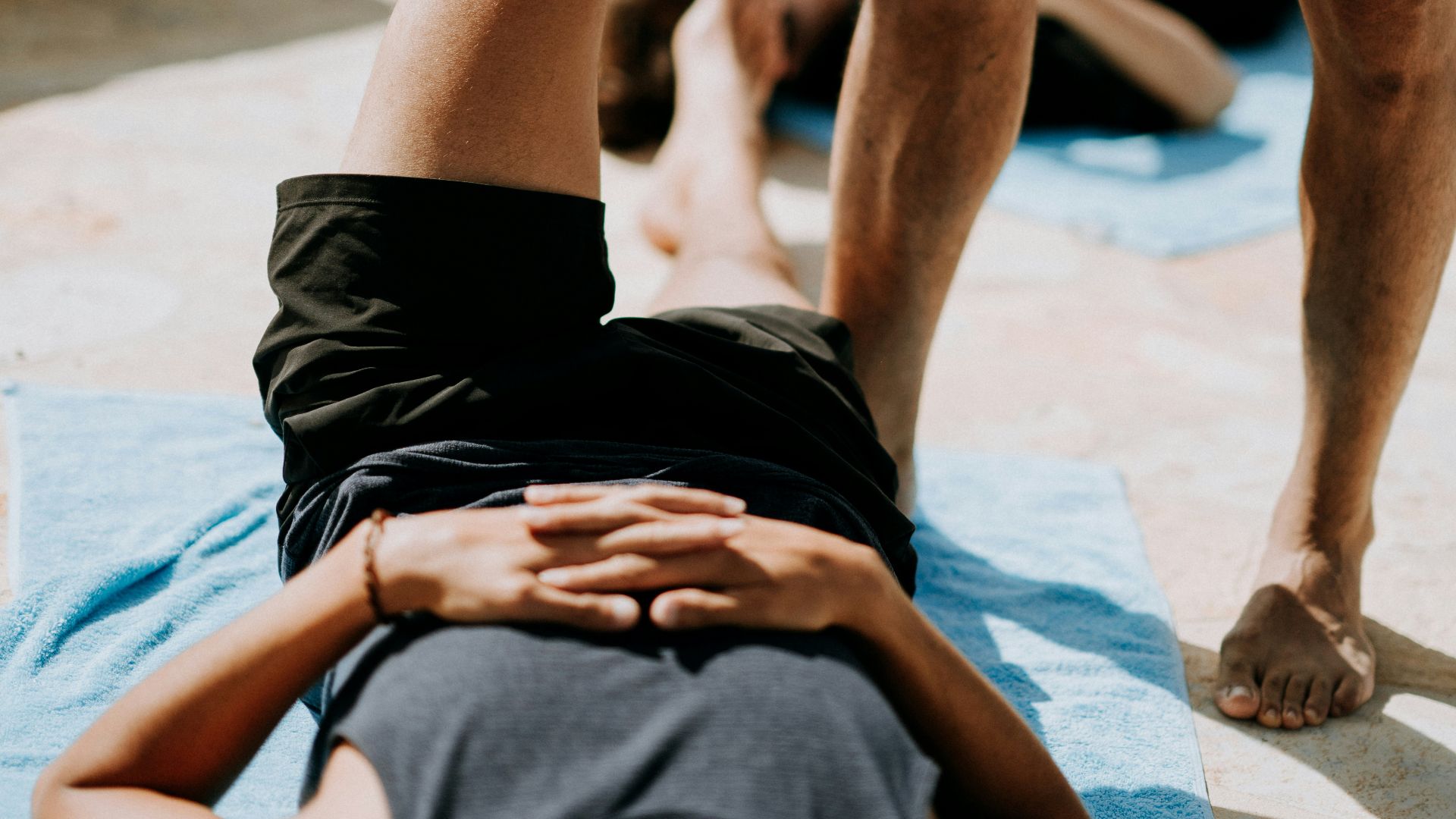 man lying on floor near man standing holding his leg