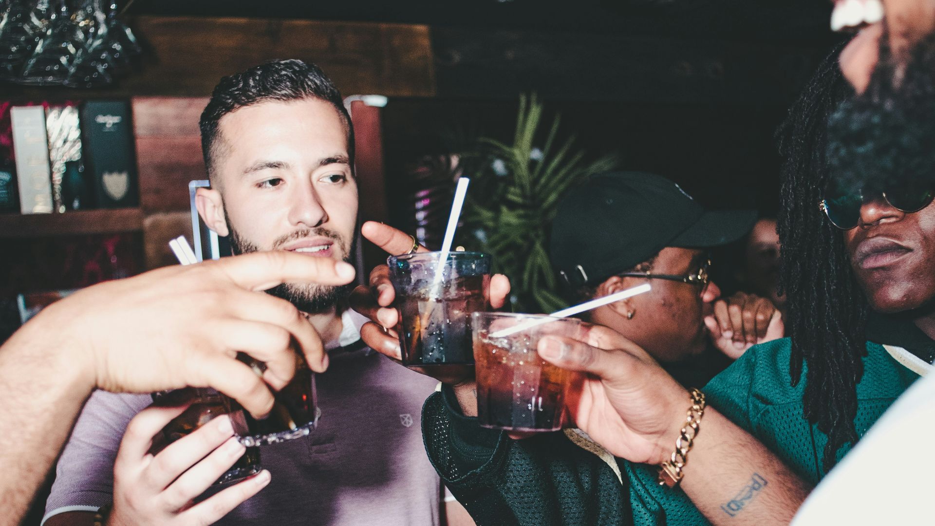 three people holding glass bottles while talking