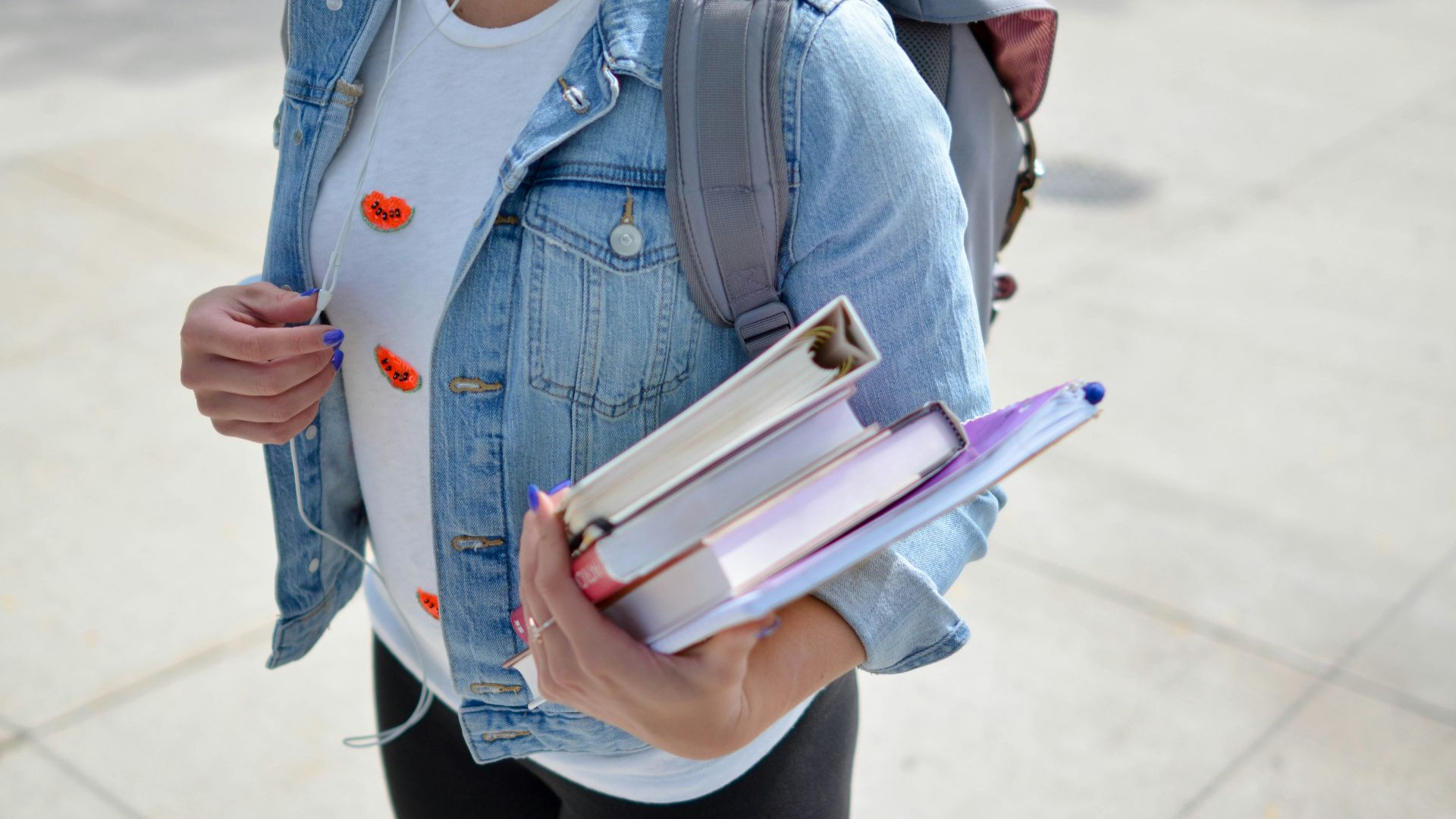 woman wearing blue denim jacket holding book