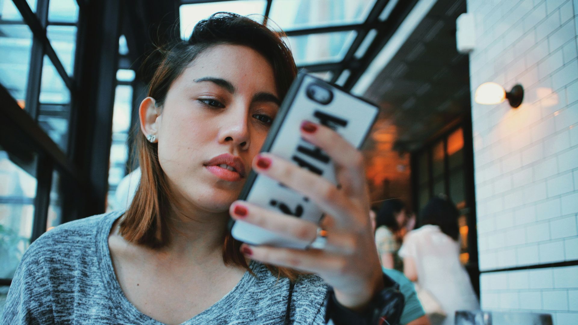 woman in gray and black sweater holding white and black iphone case