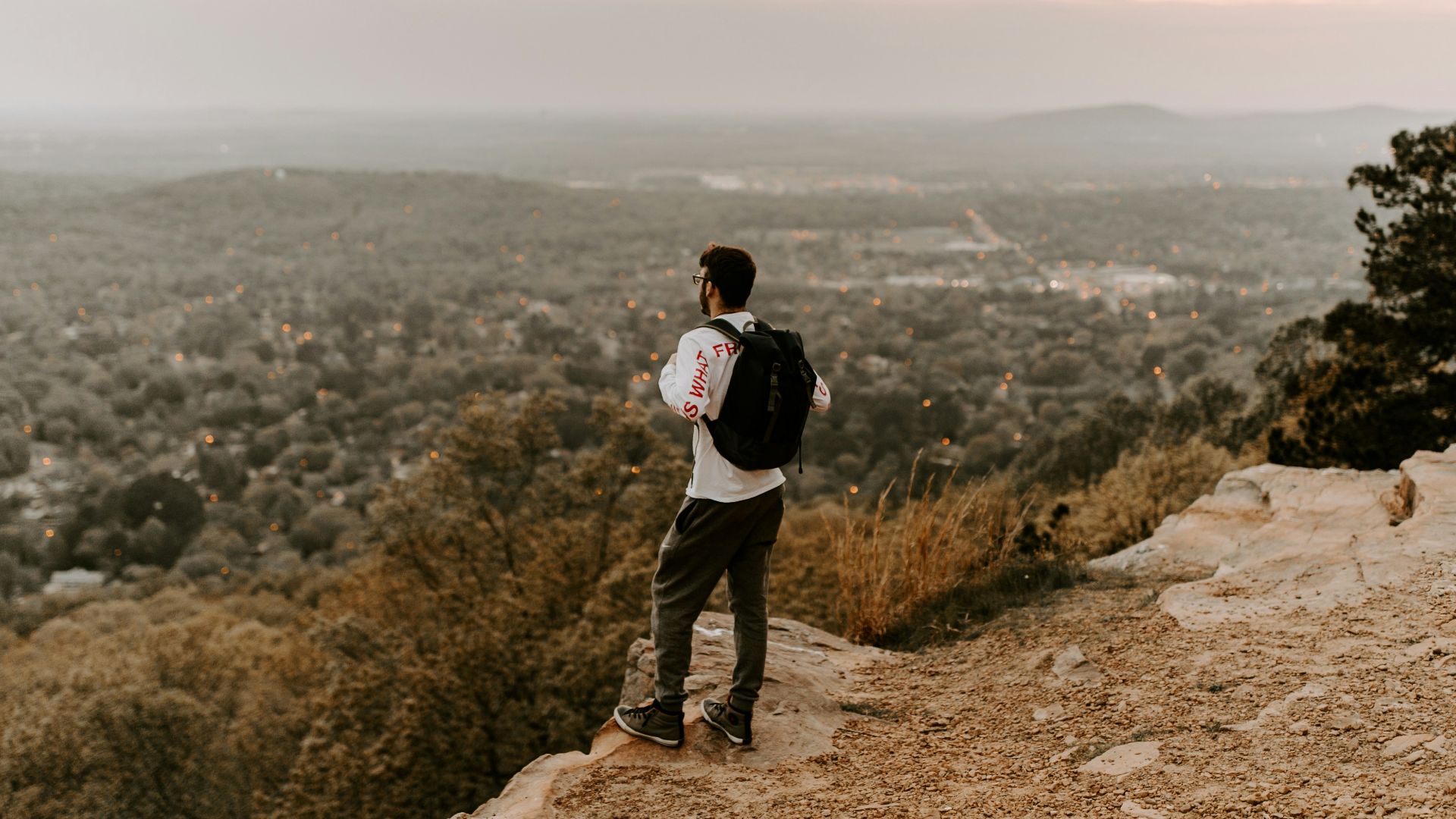 man in white shirt and black pants standing on brown rocky mountain during daytime
