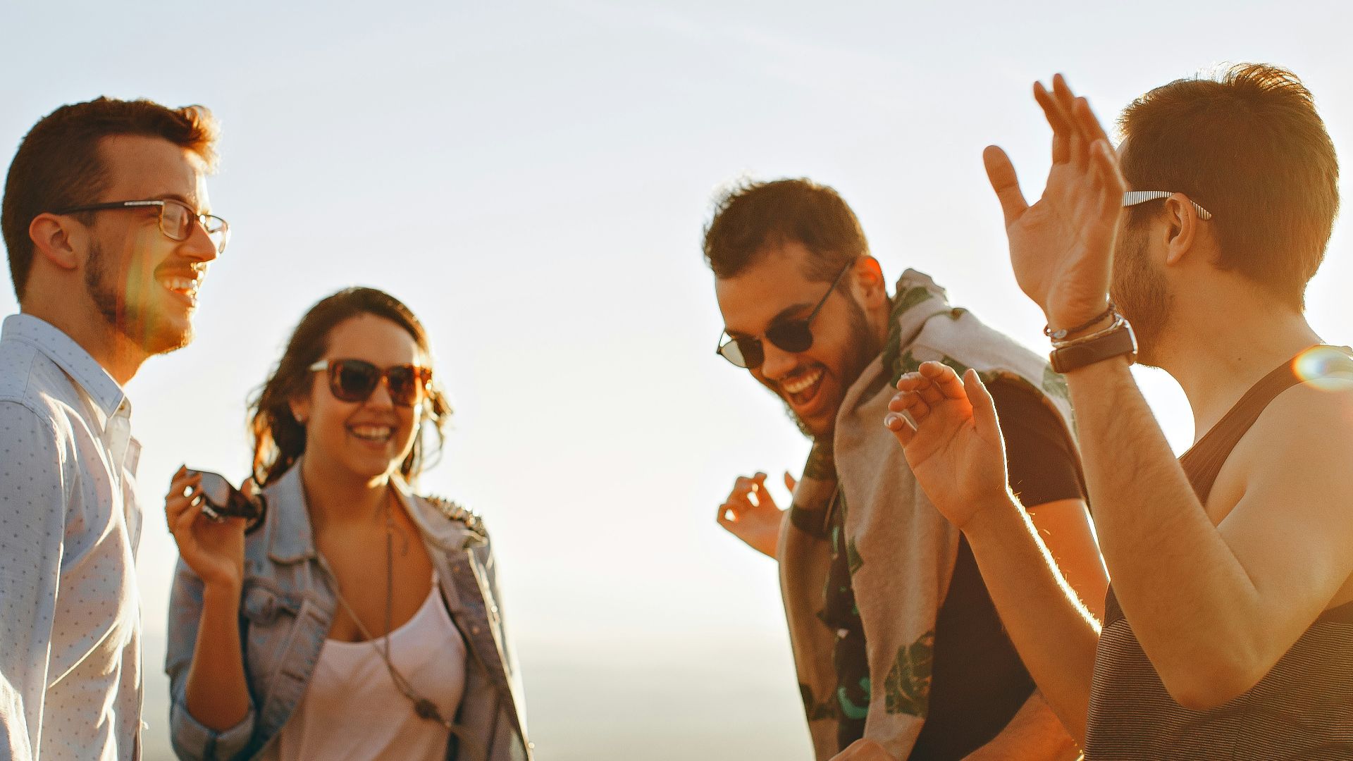 three men and one woman laughing during daytime