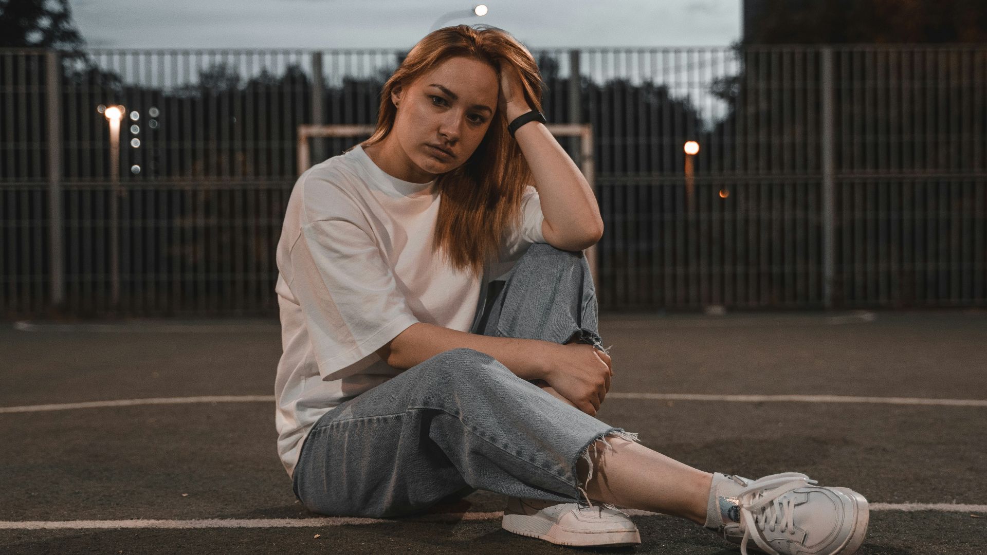 woman in white shirt and blue denim jeans sitting on road during daytime