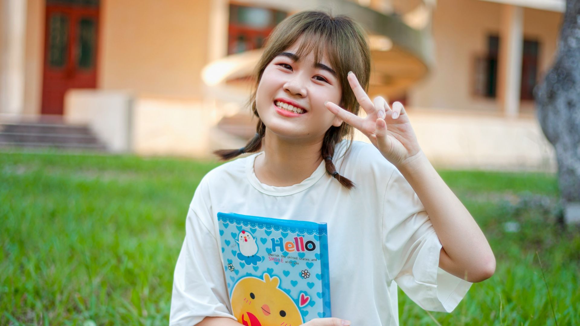 a young girl sitting in the grass holding a book