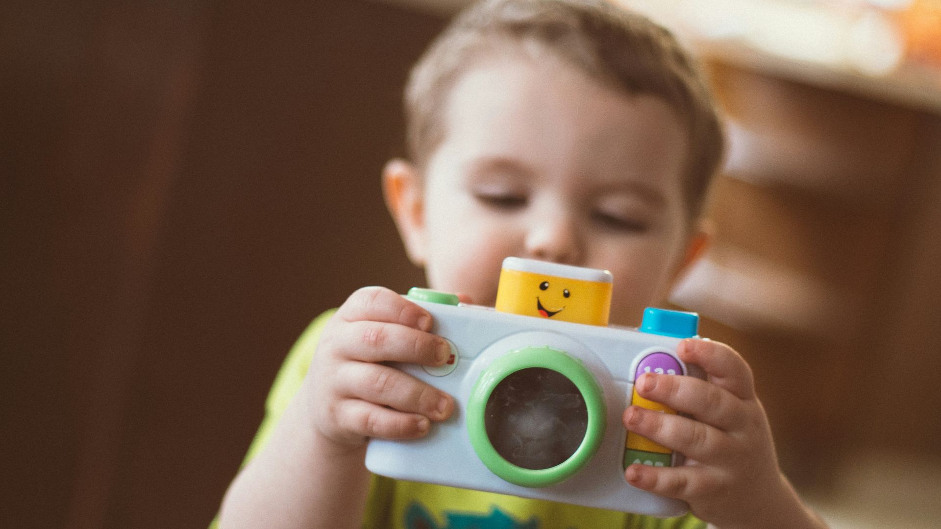 toddler holding white camera toy