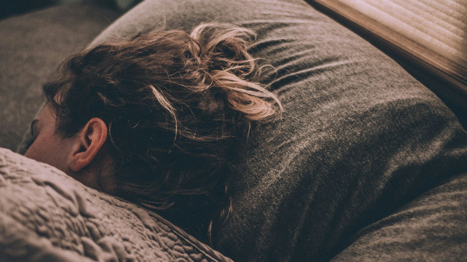 woman sleeping on bed under blankets