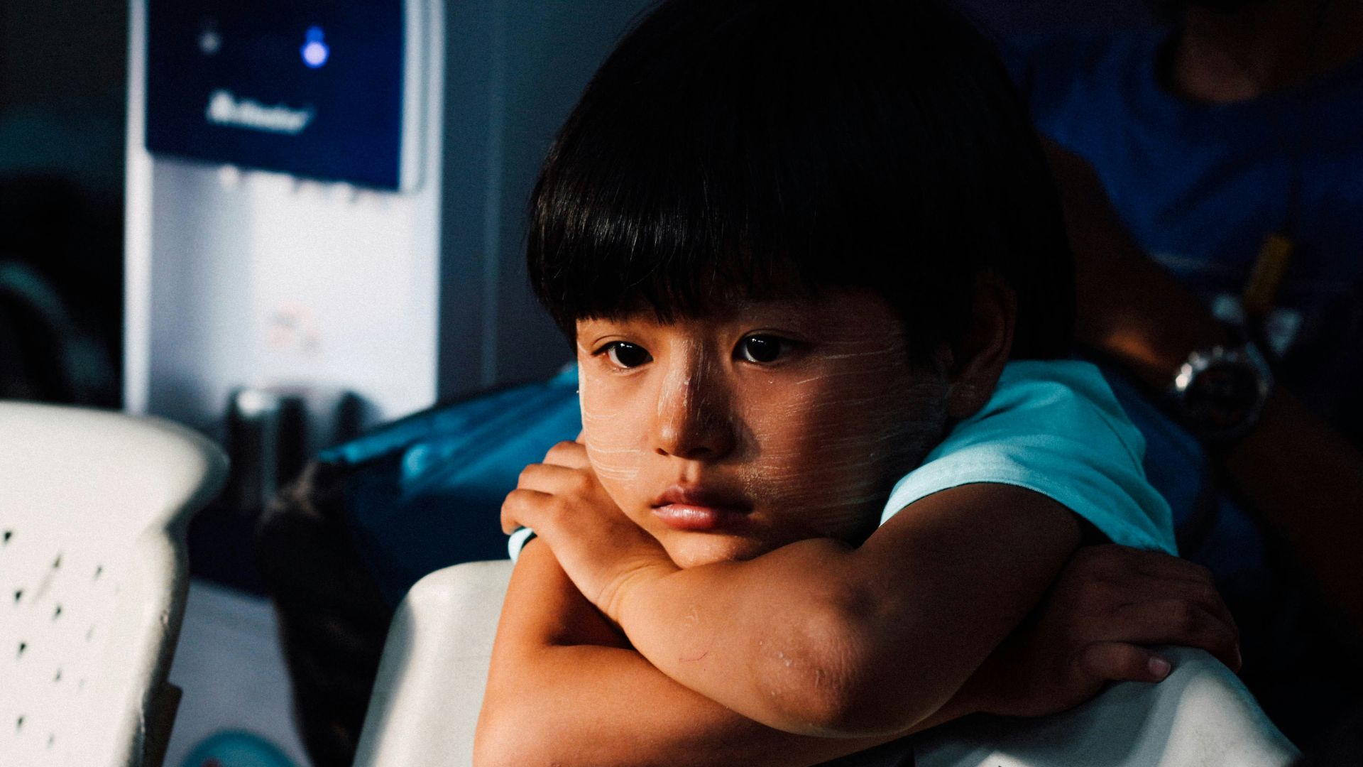 boy leaning on white chair