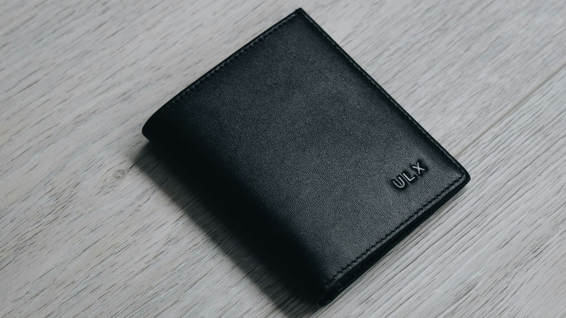 black leather bifold wallet on brown wooden table