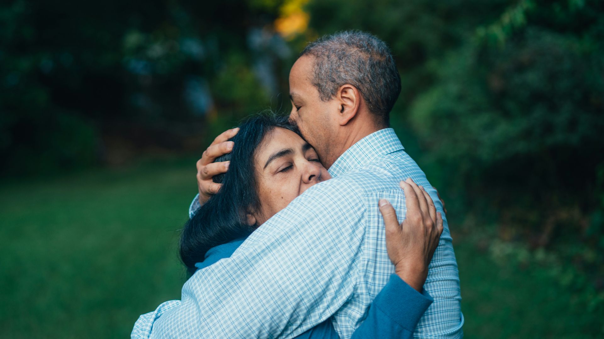 man hugging woman near trees