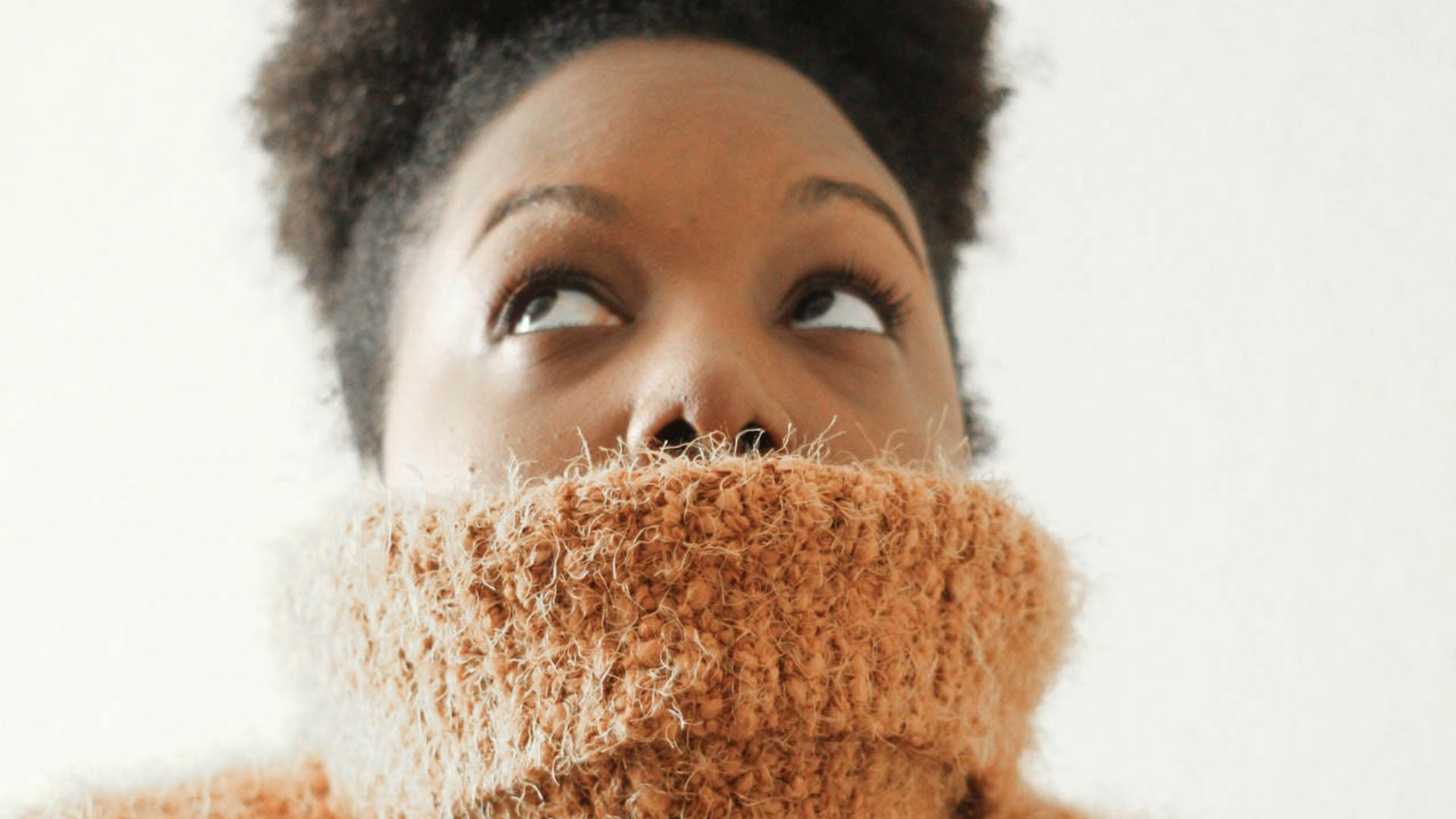 woman wearing orange turtle neck sweat shirt looking upward