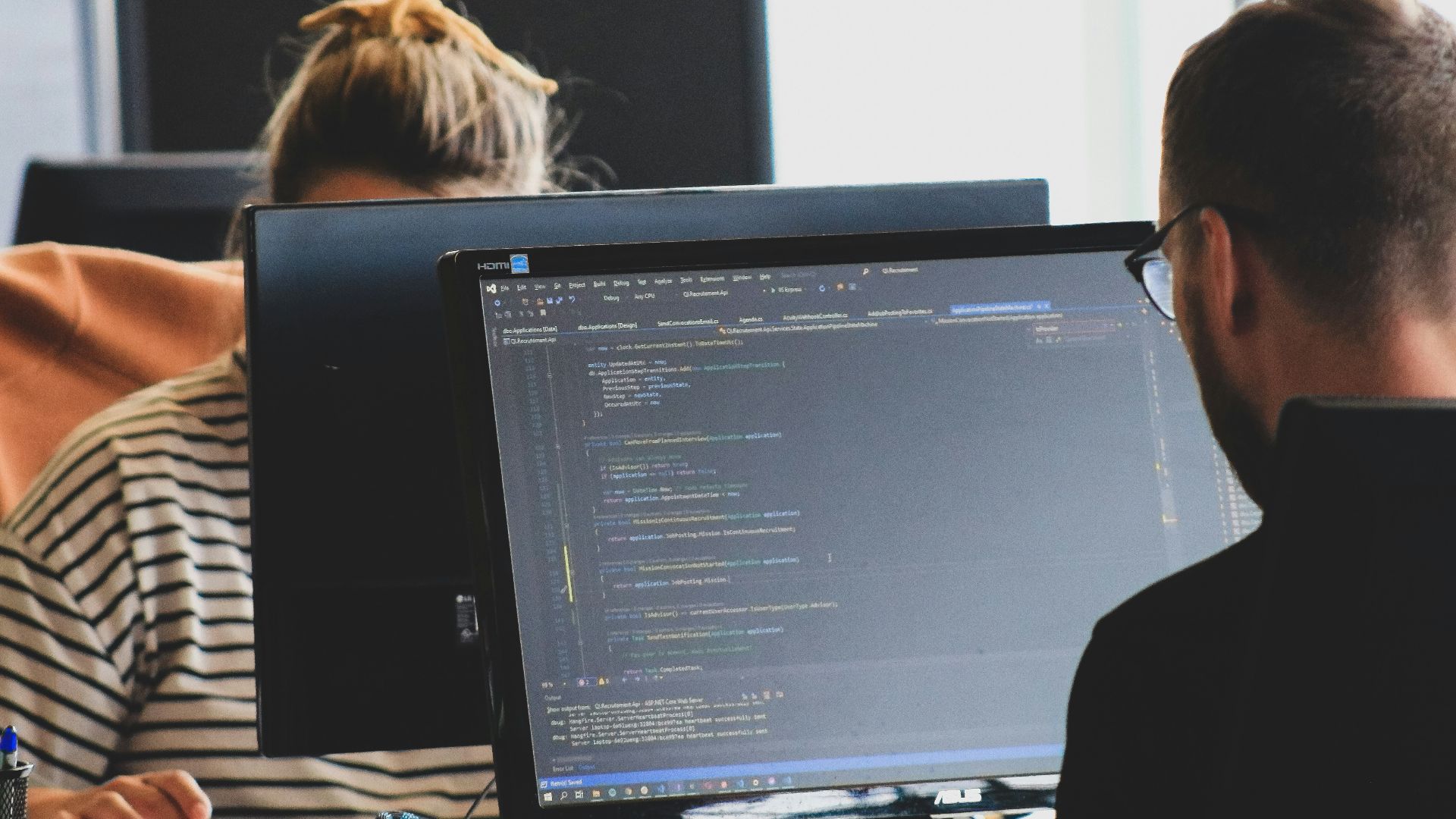 woman in black shirt sitting beside black flat screen computer monitor